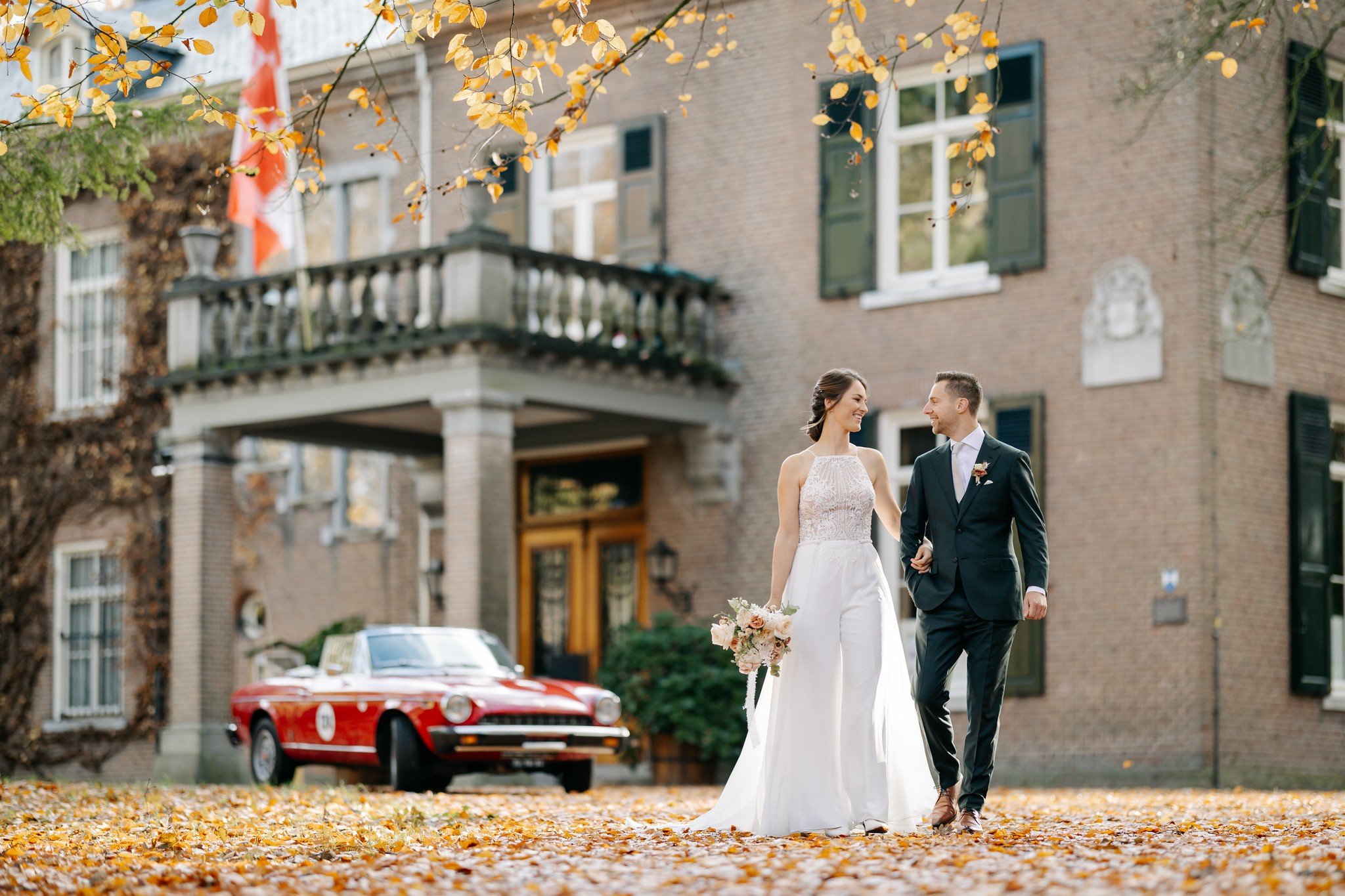 Mike &amp; Roos lopen samen tijdens de fotoshoot van hun herfstbruiloft bij Kasteelhoeve Geldrop.

Haar: @kapsalon.van.den.born 
Boeket/backdrop: @viori.eu 
@brisked_styledweddings 
Jurk: @mariagebruidsmode 
Pak: s@suitsupply 
Trouwlocatie: @kasteelh