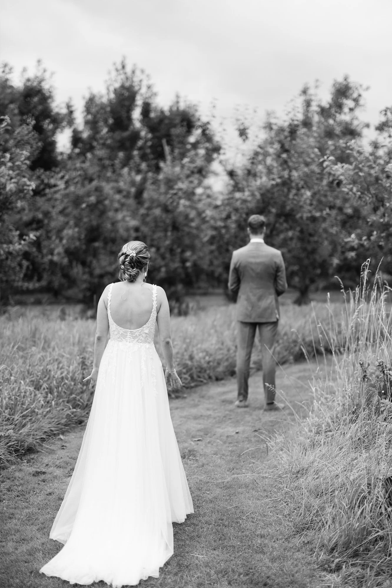  Bruid loopt naar bruidegom toe tijdens de first look in de boomgaard 