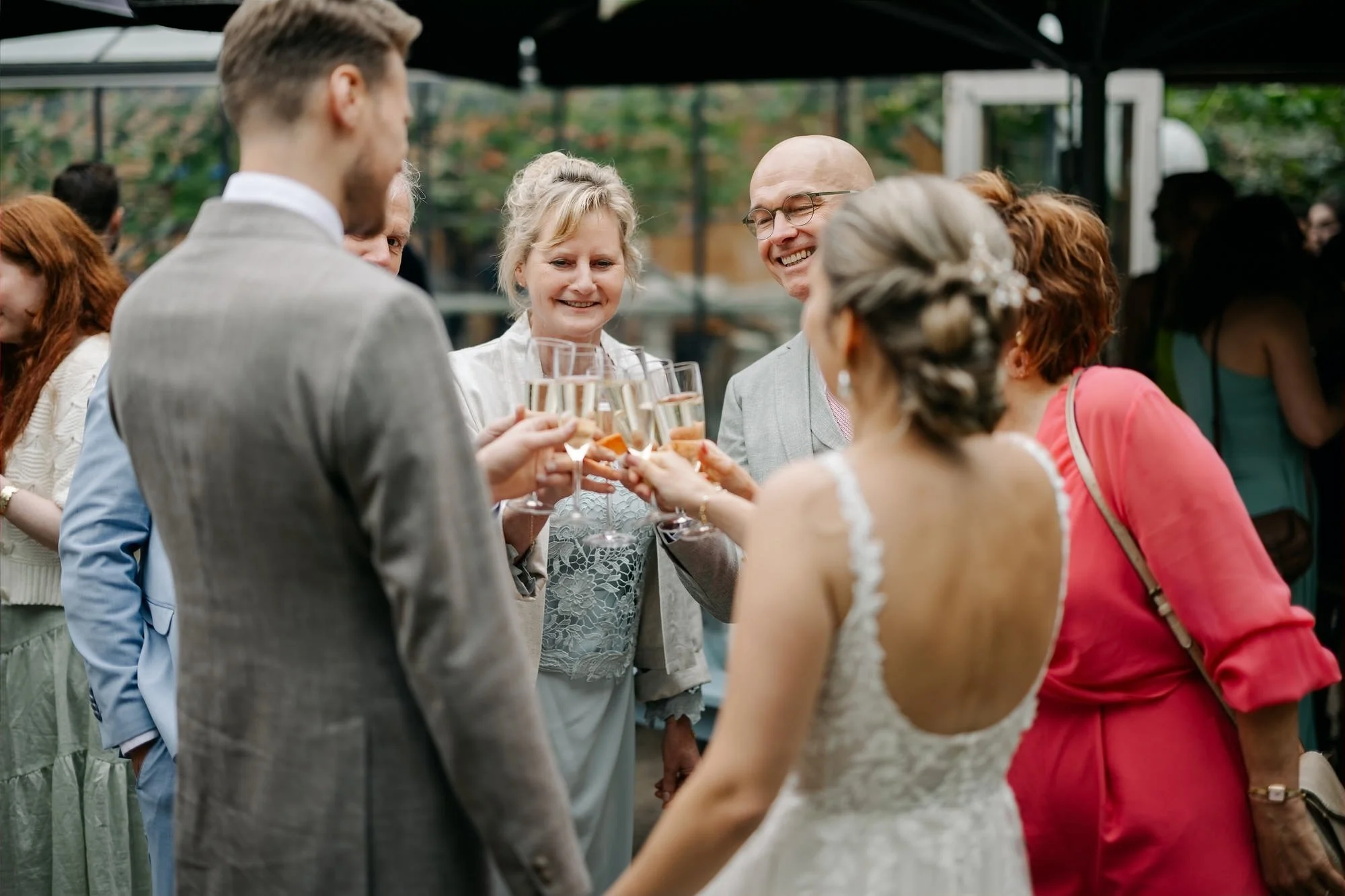  Bruidspaar klinkt met ouders en familie tijdens de receptie in de tuin 