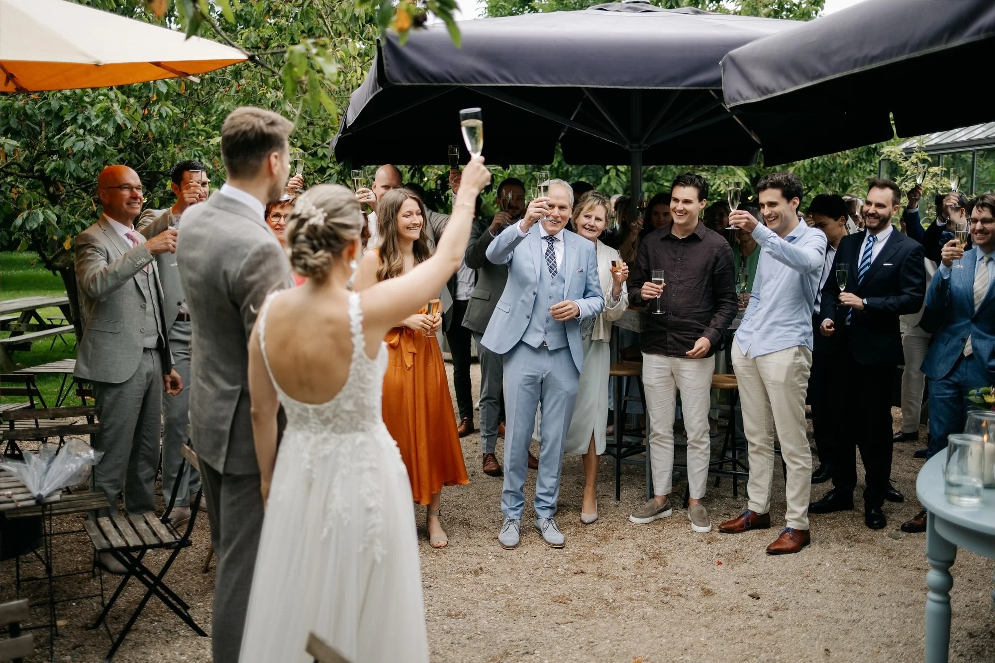  Bruidspaar heft het glas met alle gasten tijdens de receptie buiten 