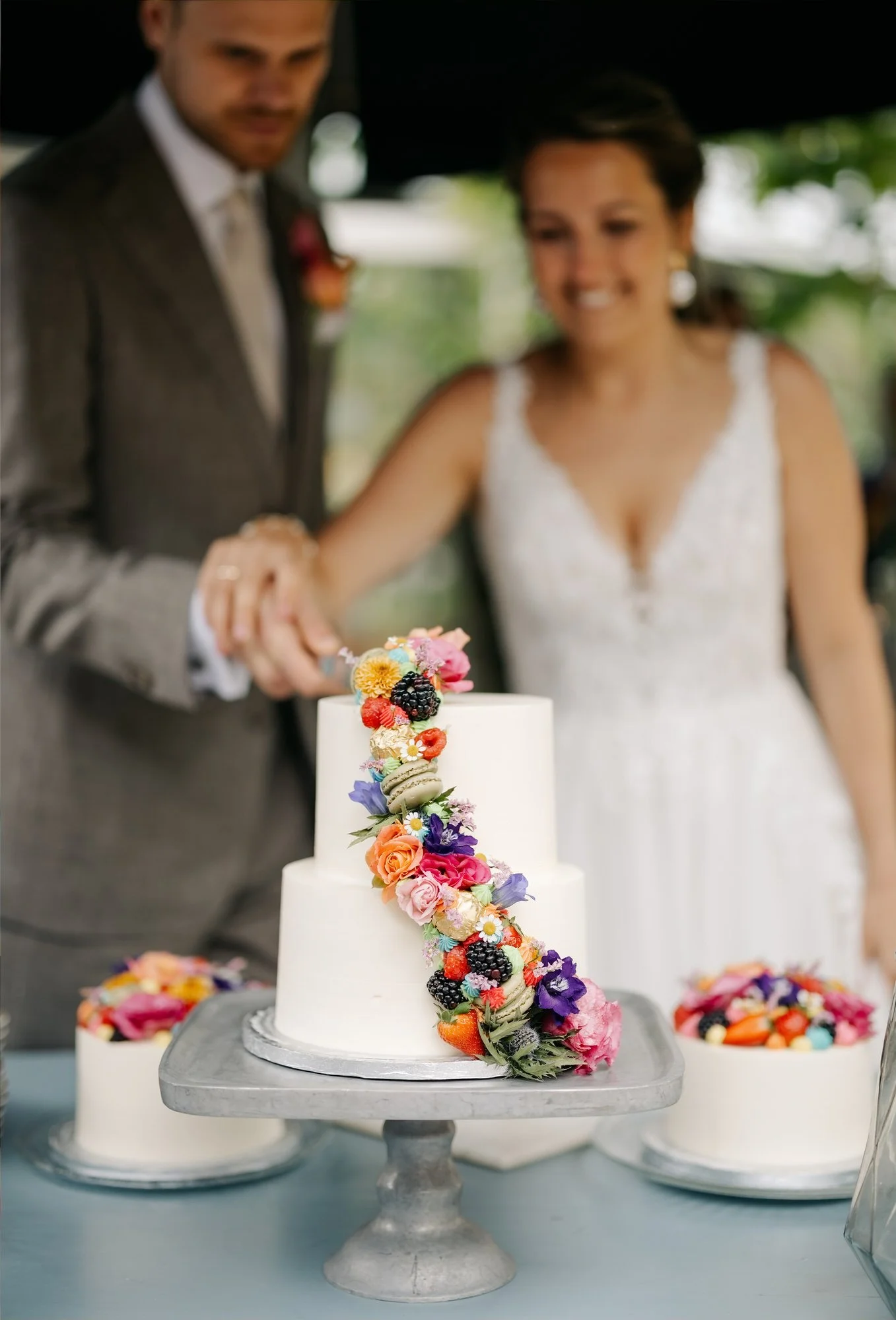  Bruidspaar snijdt de bruidstaart aan met bloemen en macarons 