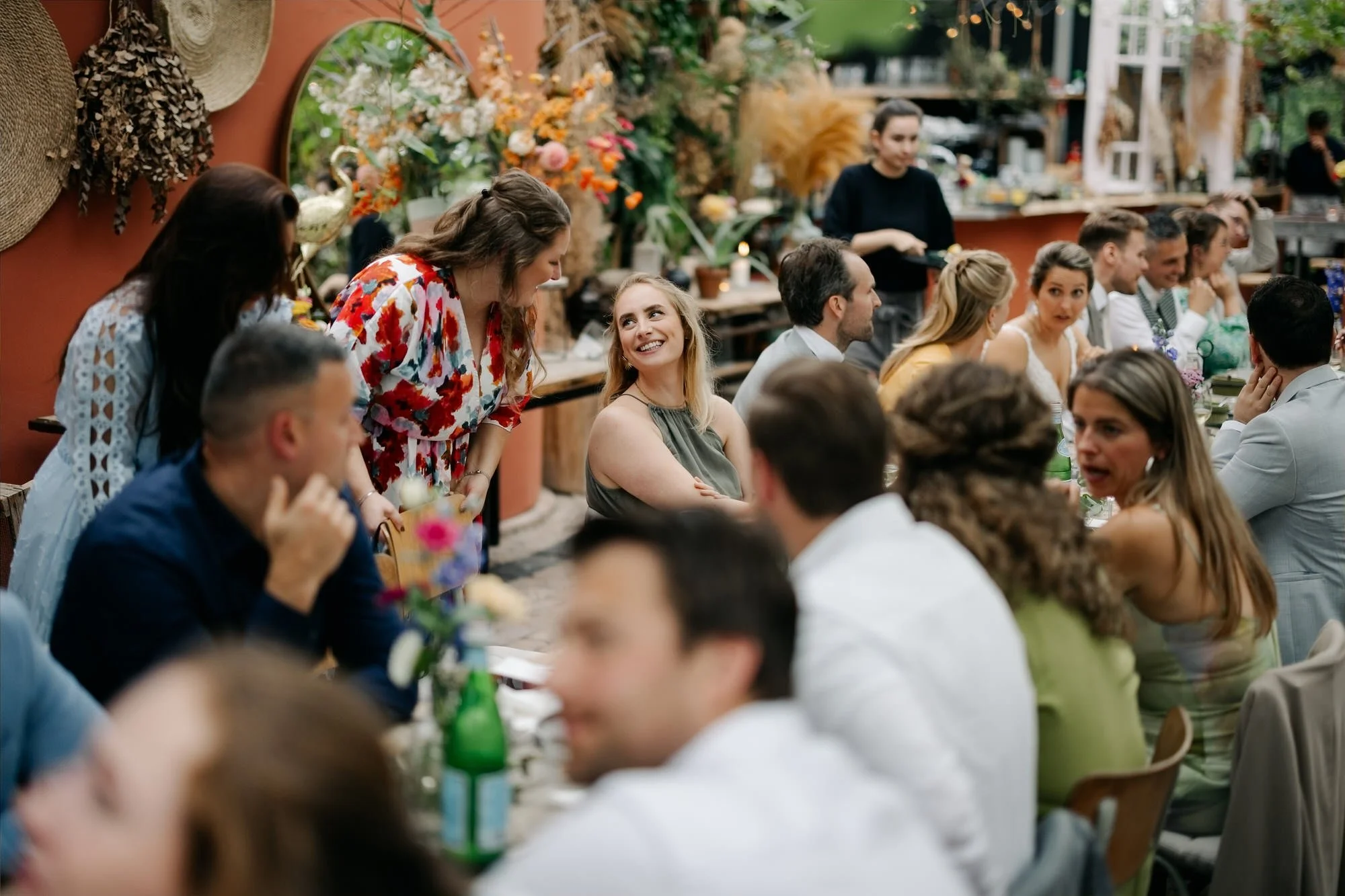  Gasten genieten van het diner in de kas met terracotta muur op de achtergrond 