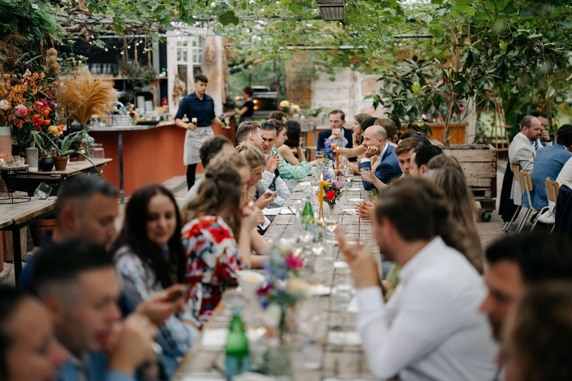  Volle dinertafel met gasten in de glazen kas tijdens de bruiloft 