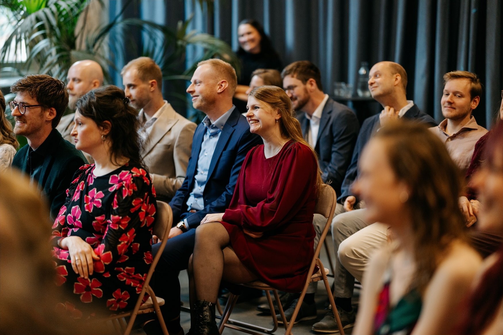  Gasten zitten op vouwstoelen te kijken naar de ceremonie in de zaal 