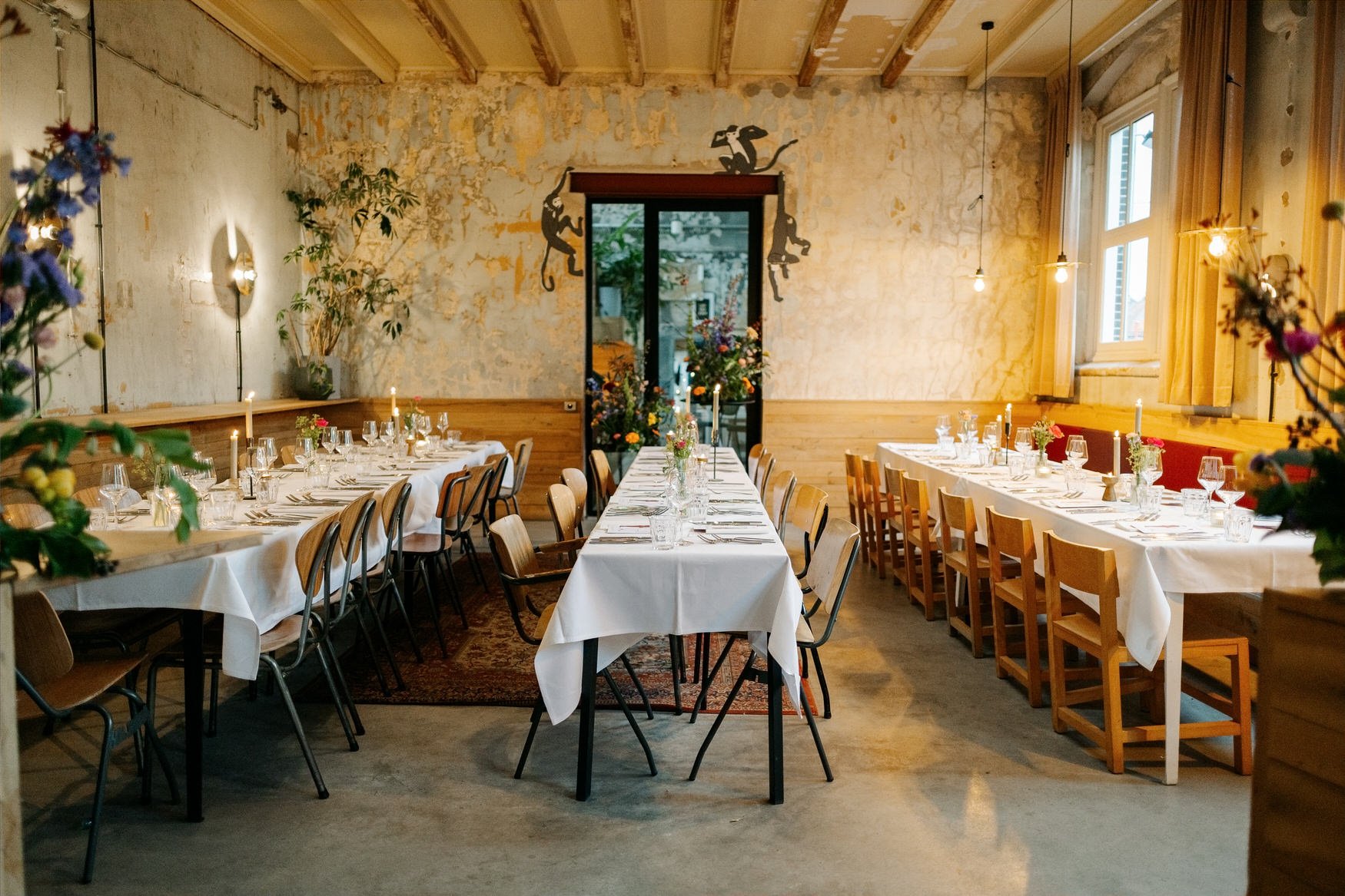  dinnerzaal met lange tafels, bloemen en kaarslicht klaar voor het diner 