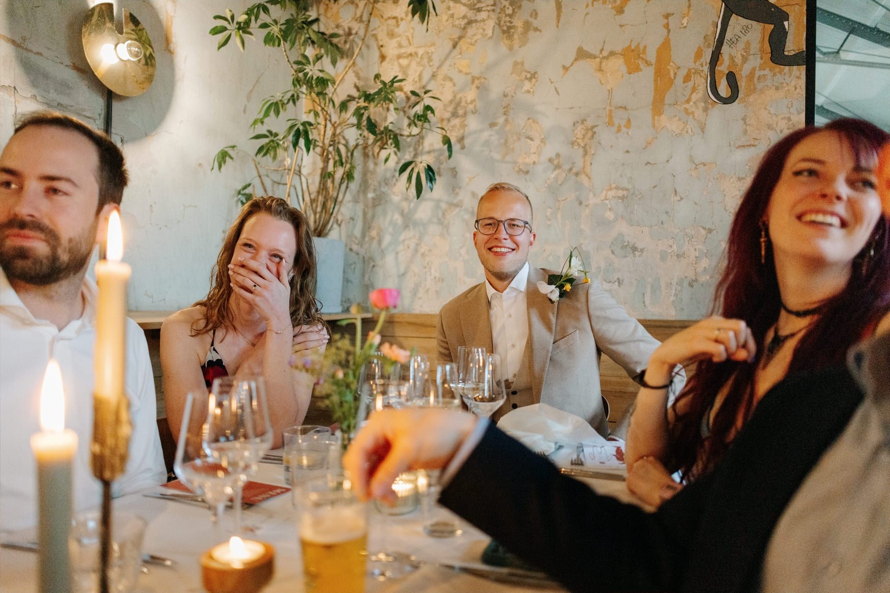  Gasten lachen samen aan de kaarsverlichte dinertafel 