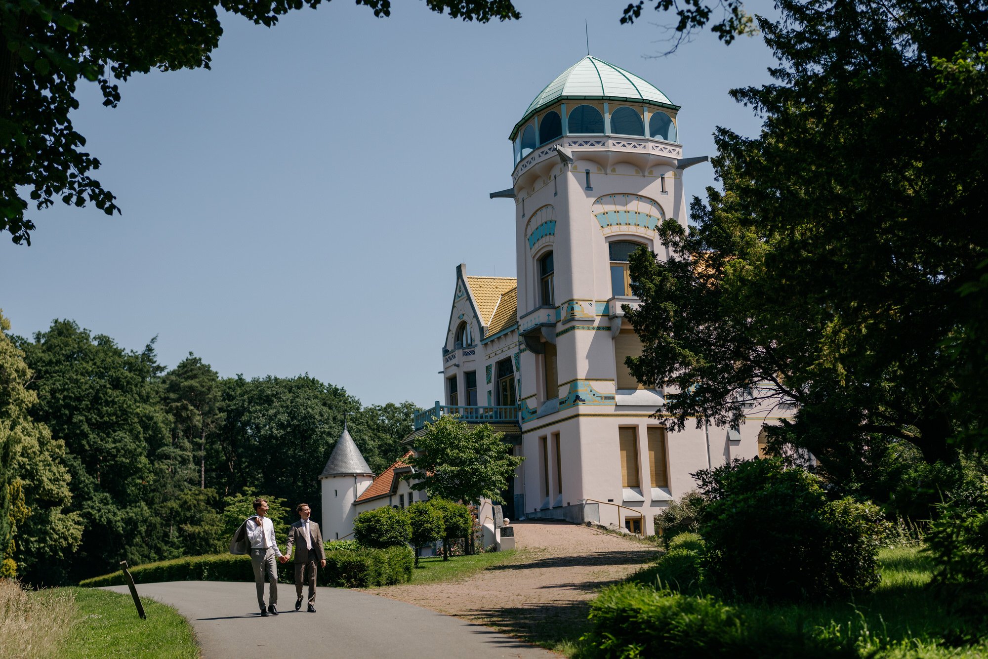  bruidegoms wandelen over het landgoed met Jachtslot Mookerheide op de achtergrond 