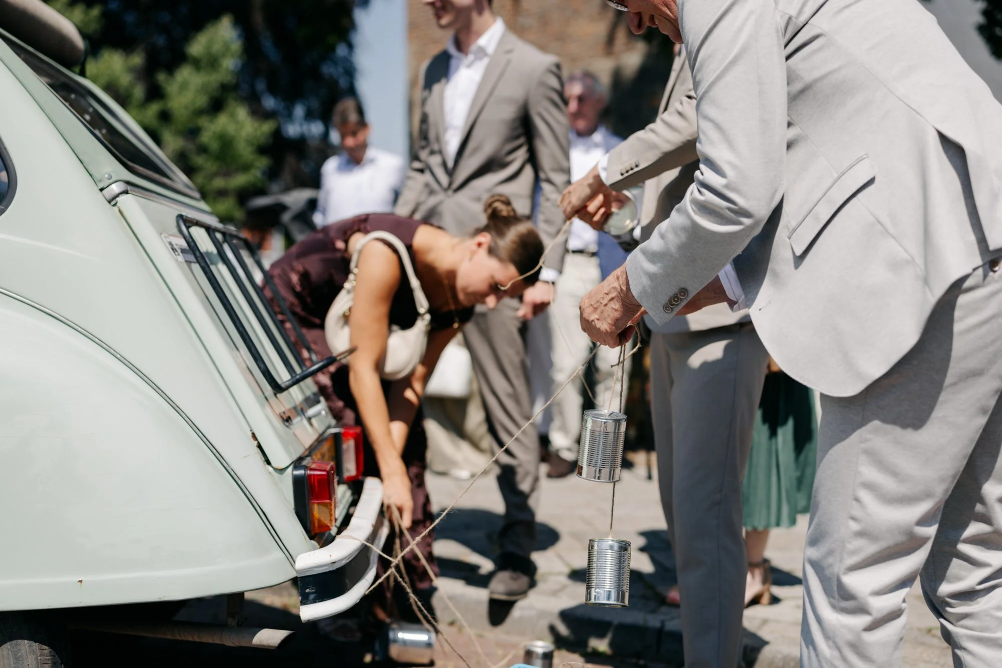  gasten versieren de bruidsauto met blikken aan touwtjes 