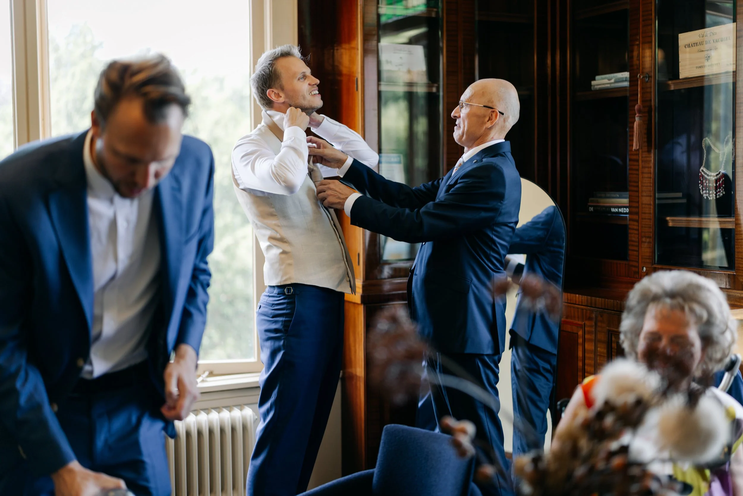  Bruidegom Ivo wordt geholpen met zijn overhemd door een familielid tijdens de getting ready bij Jachtslot Mookerheide. 