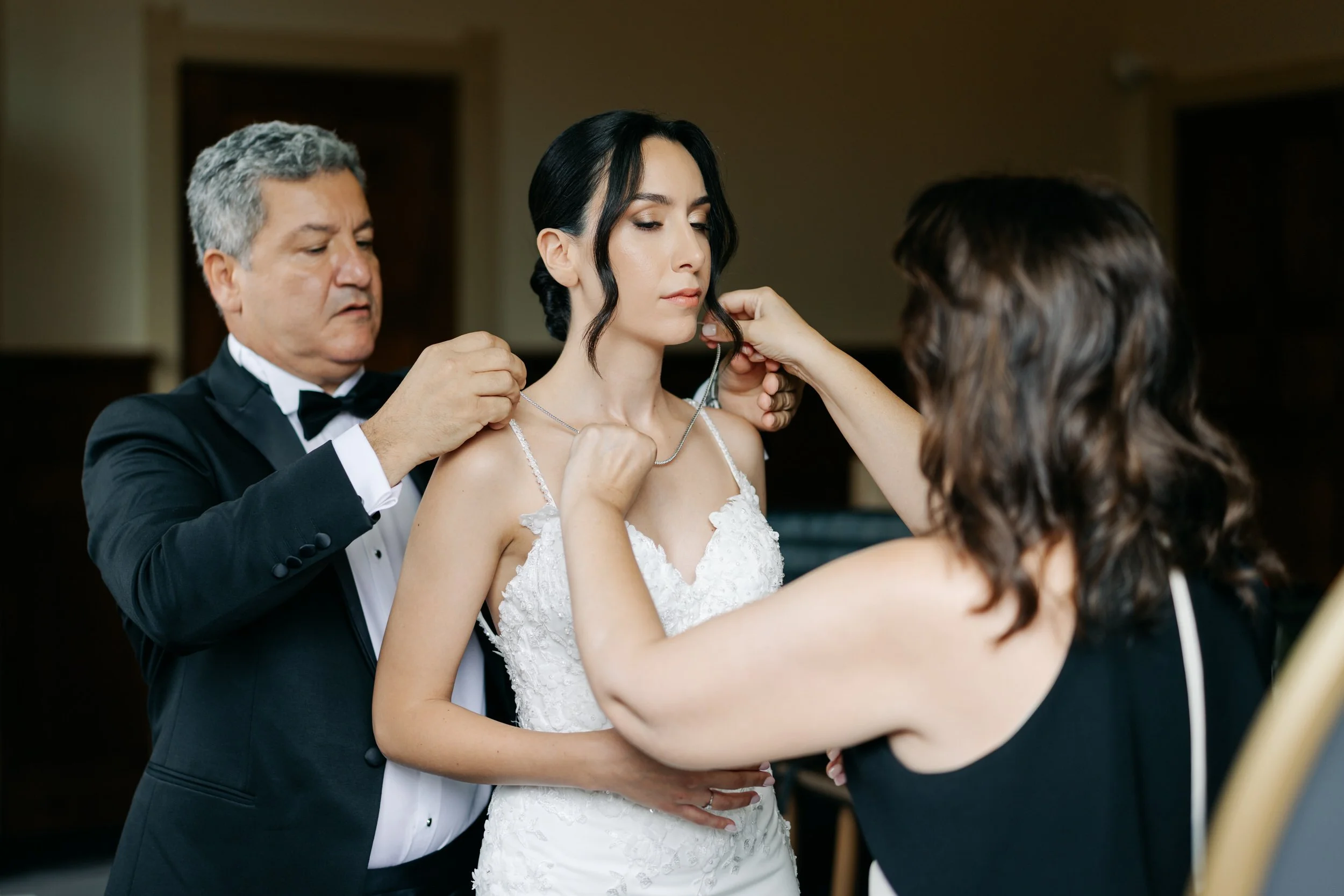  Vader maakt de ketting van de bruid vast terwijl moeder meehelpt met de laatste details voor de ceremonie. 