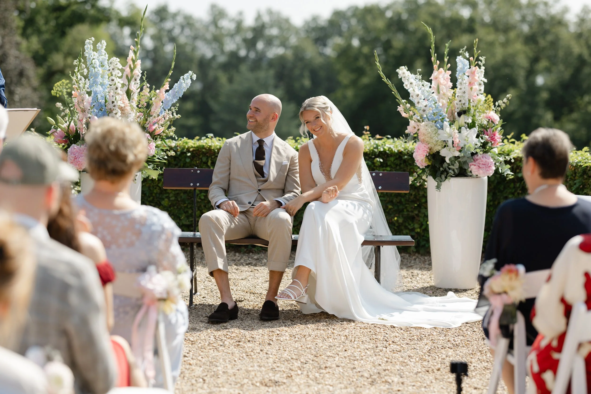 Bruidspaar zit samen tijdens een ceremonie in de buitenlucht, reportagebeeld van een intiem moment op de trouwdag