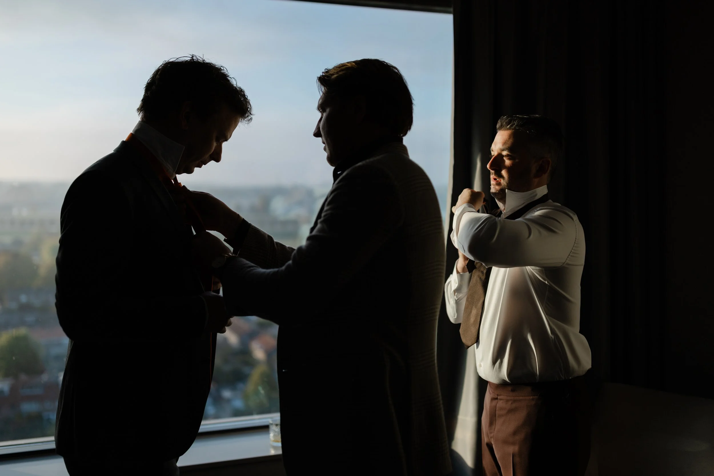 Silhouet van vrienden van de bruidegom en de bruidegom tijdens het aankleed moment in de ochtend.