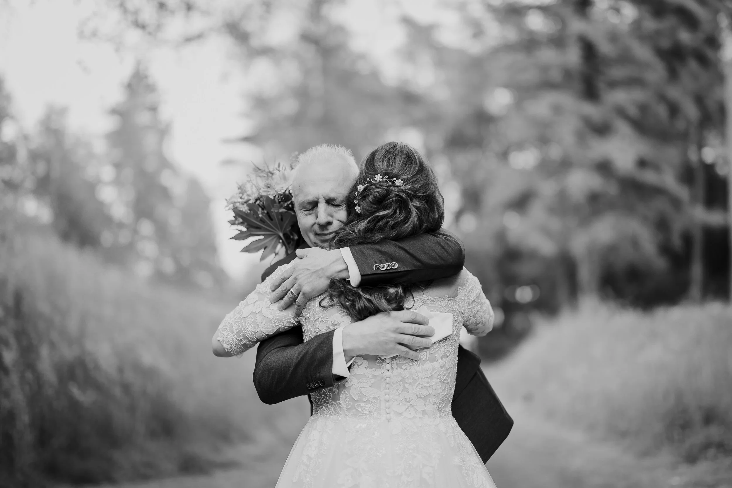 Emotionele omhelzing tussen bruid en haar vader tijdens de trouwdag, zwart wit moment uit een trouwreportage