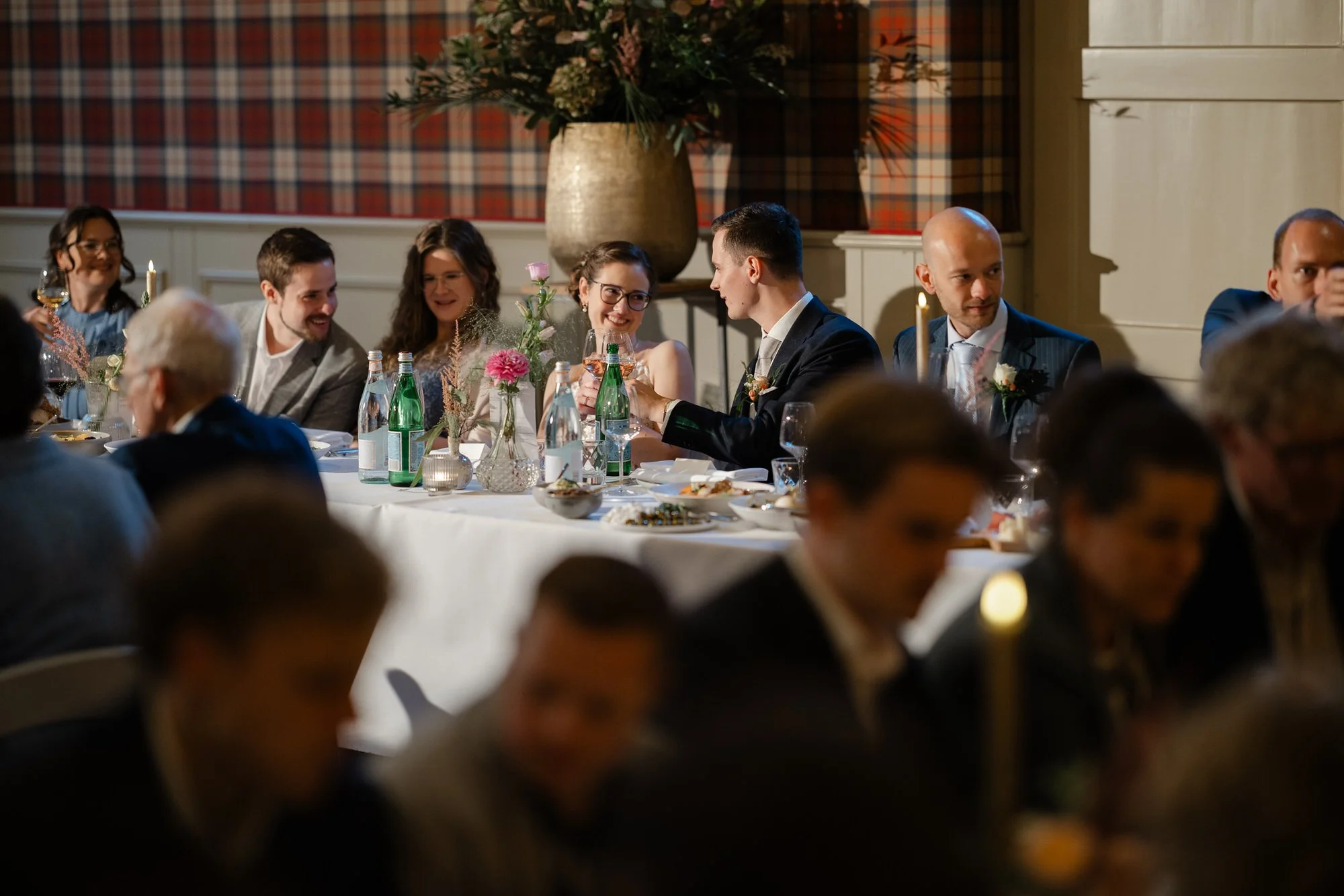“Spontaan moment tijdens het diner op een bruiloft, vastgelegd met flitslicht om sfeer en diepte te behouden in weinig licht.”