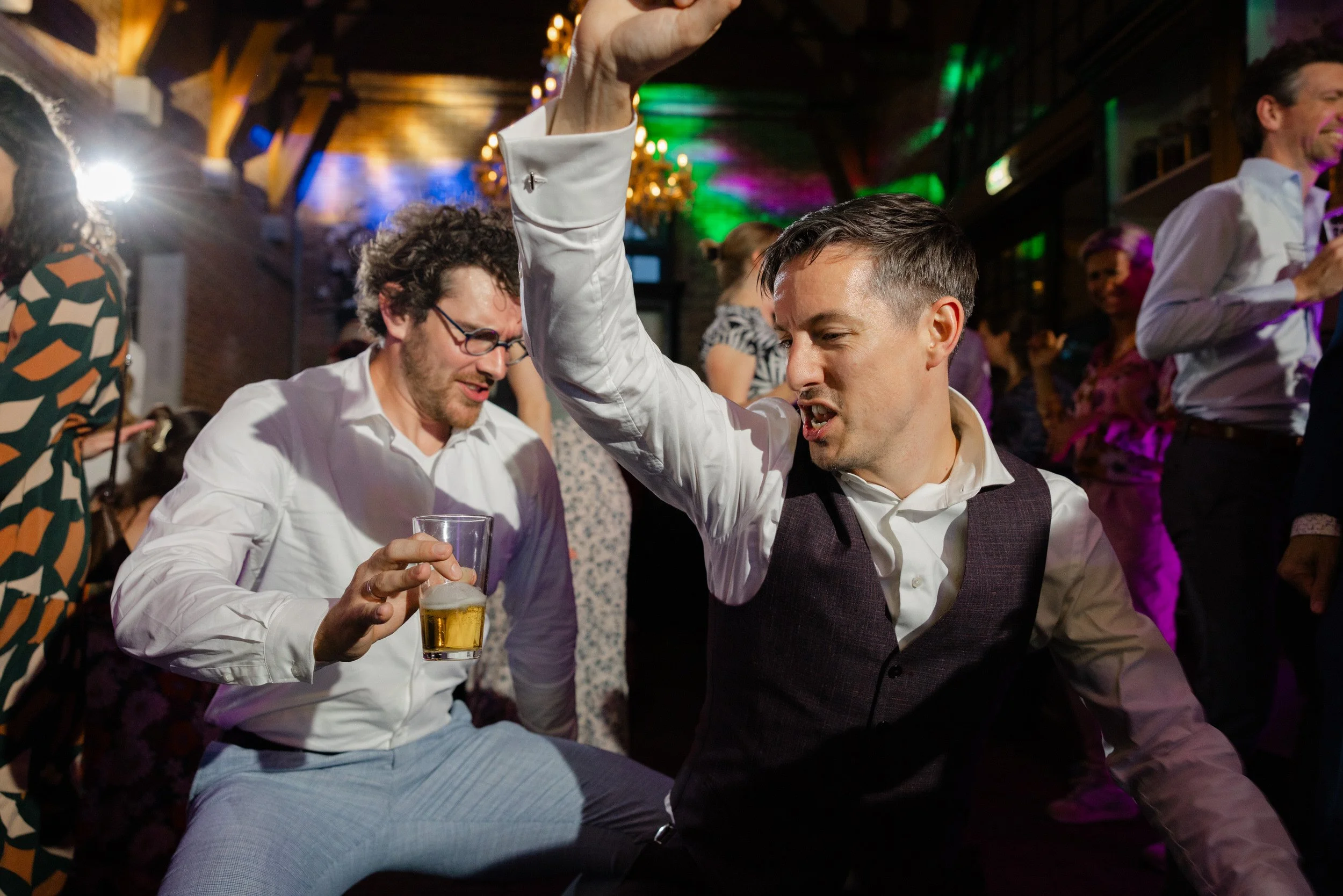 Bruidegom en gasten dansen uitbundig op het feest tijdens de bruiloft, spontaan moment vol energie en plezier