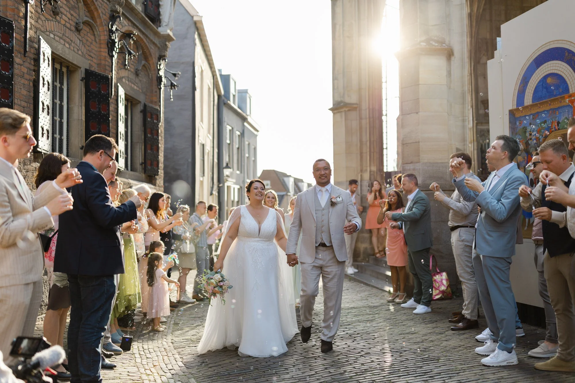 Bruidspaar loopt hand in hand door het centrum van Nijmegen na de ceremonie, omringd door gasten