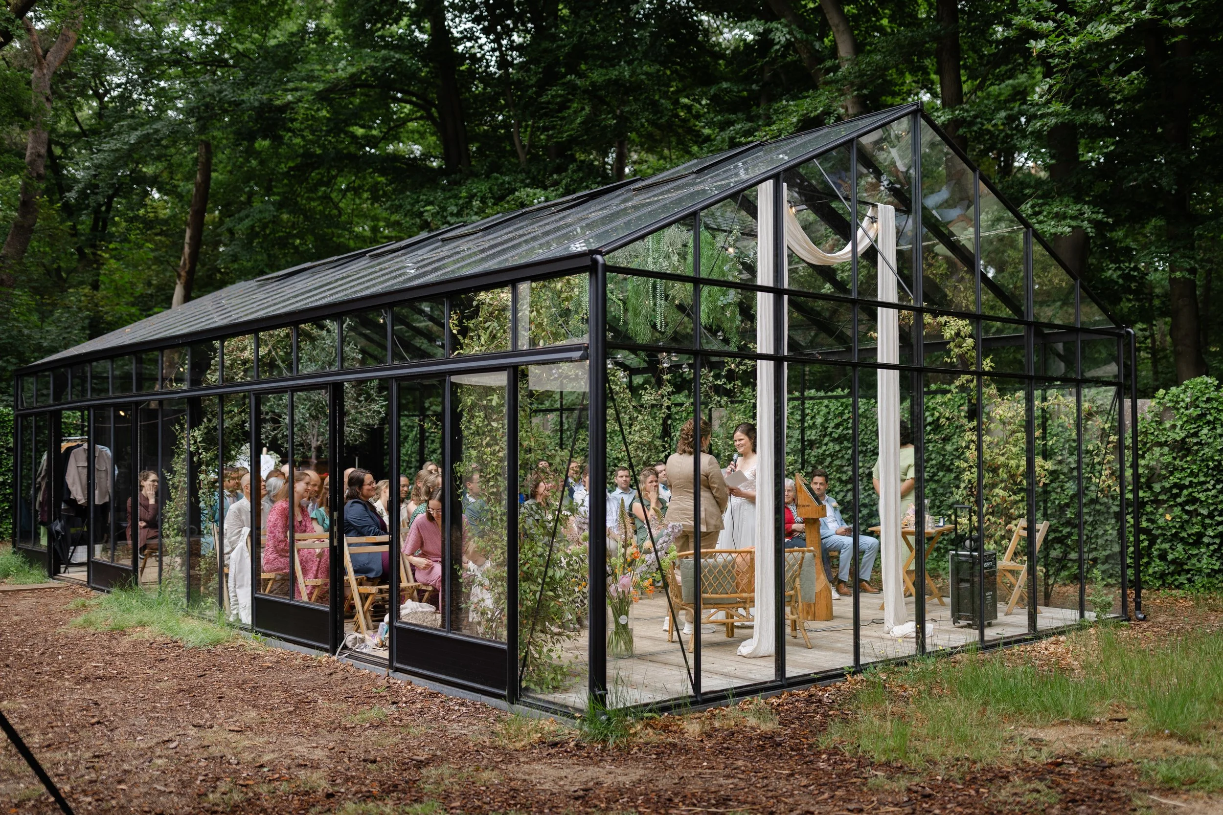 Ceremonie in de glazen boskas bij Villa Klein Heumen tijdens de bruiloft van Evelien en Monique