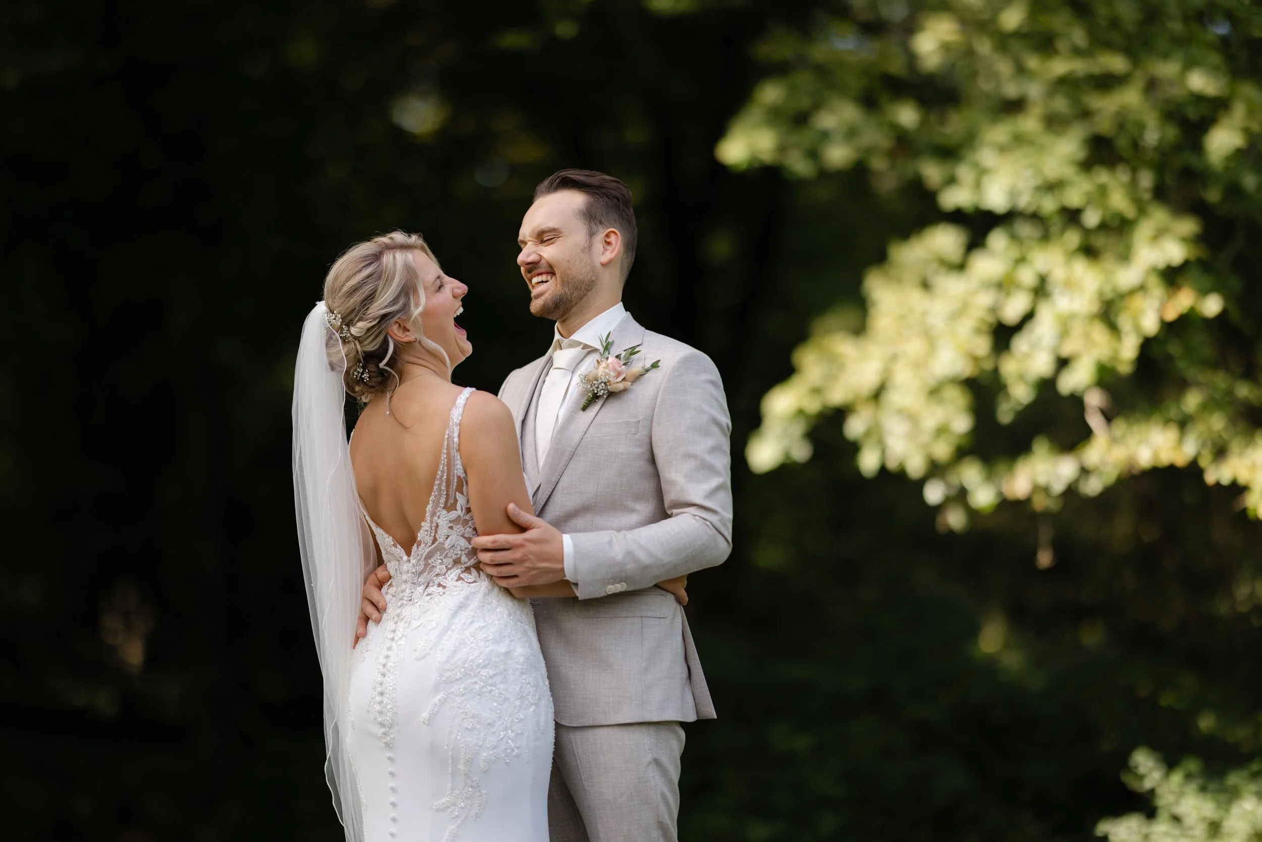 uidspaar staat samen in het groen tijdens een rustig moment op de trouwdag, romantische trouwfoto met zachte achtergrond