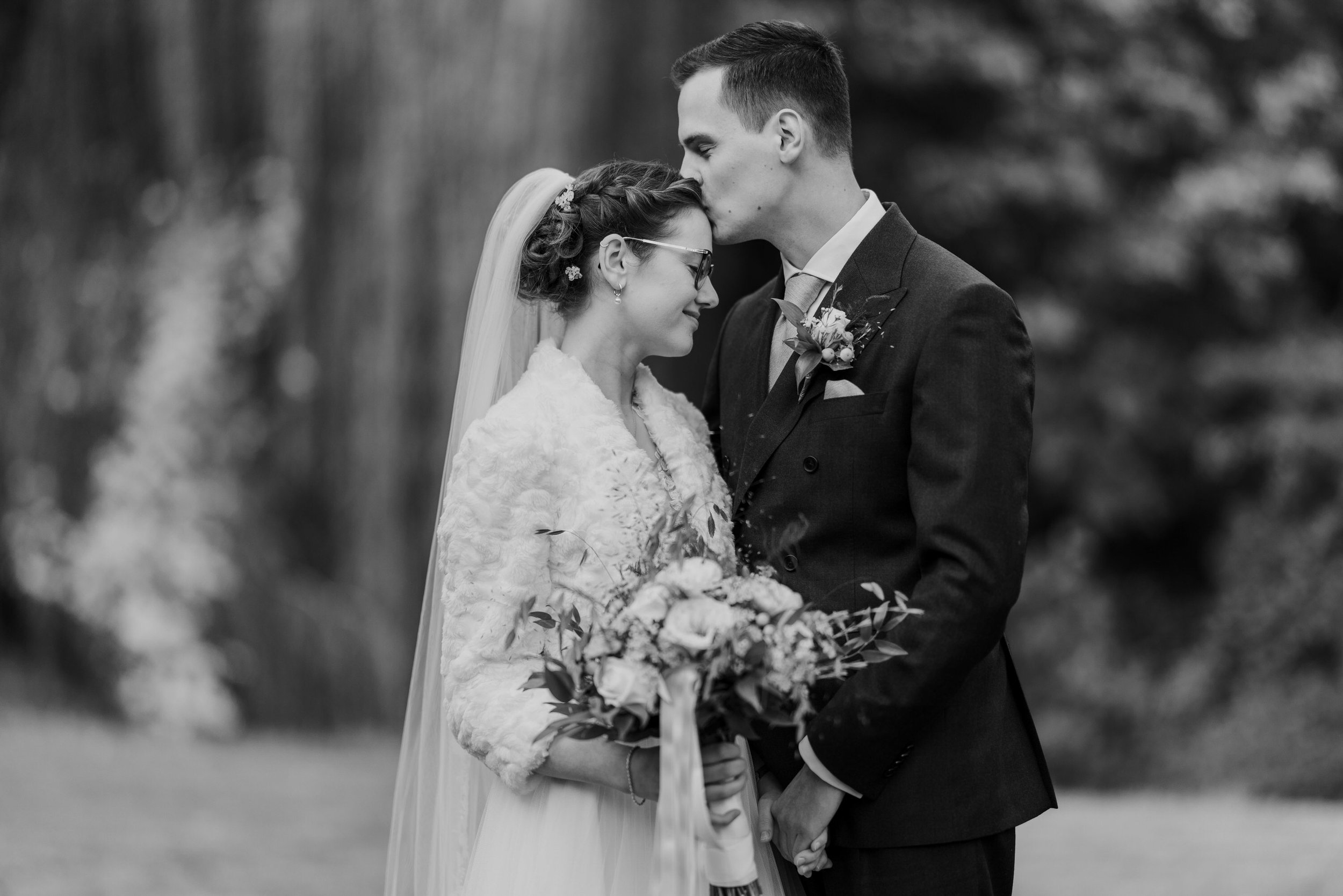 “Rustig en intiem zwart-wit portret van het bruidspaar tijdens de fotoshoot, vastgelegd met een 85mm lens.”
