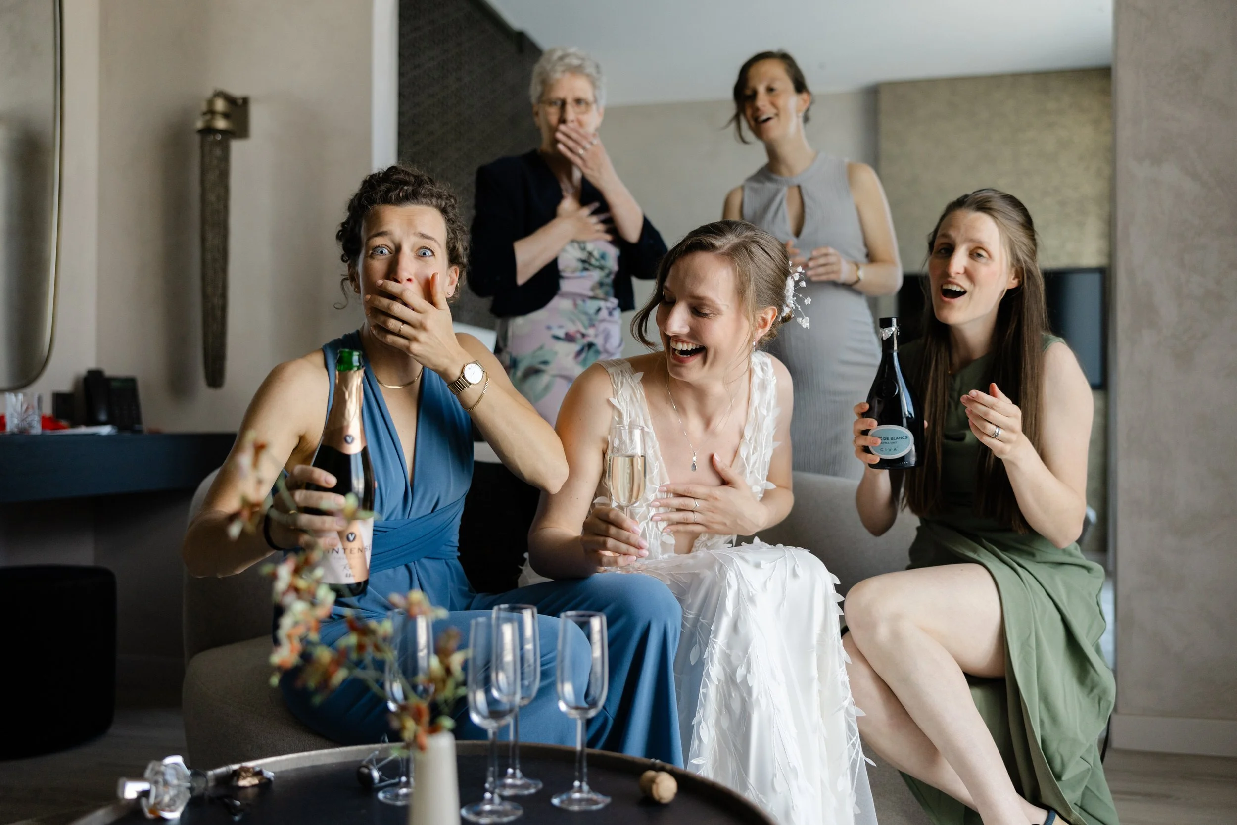 Bruid en bruidsmeisjes reageren enthousiast met champagne tijdens de voorbereidingen op de trouwdag