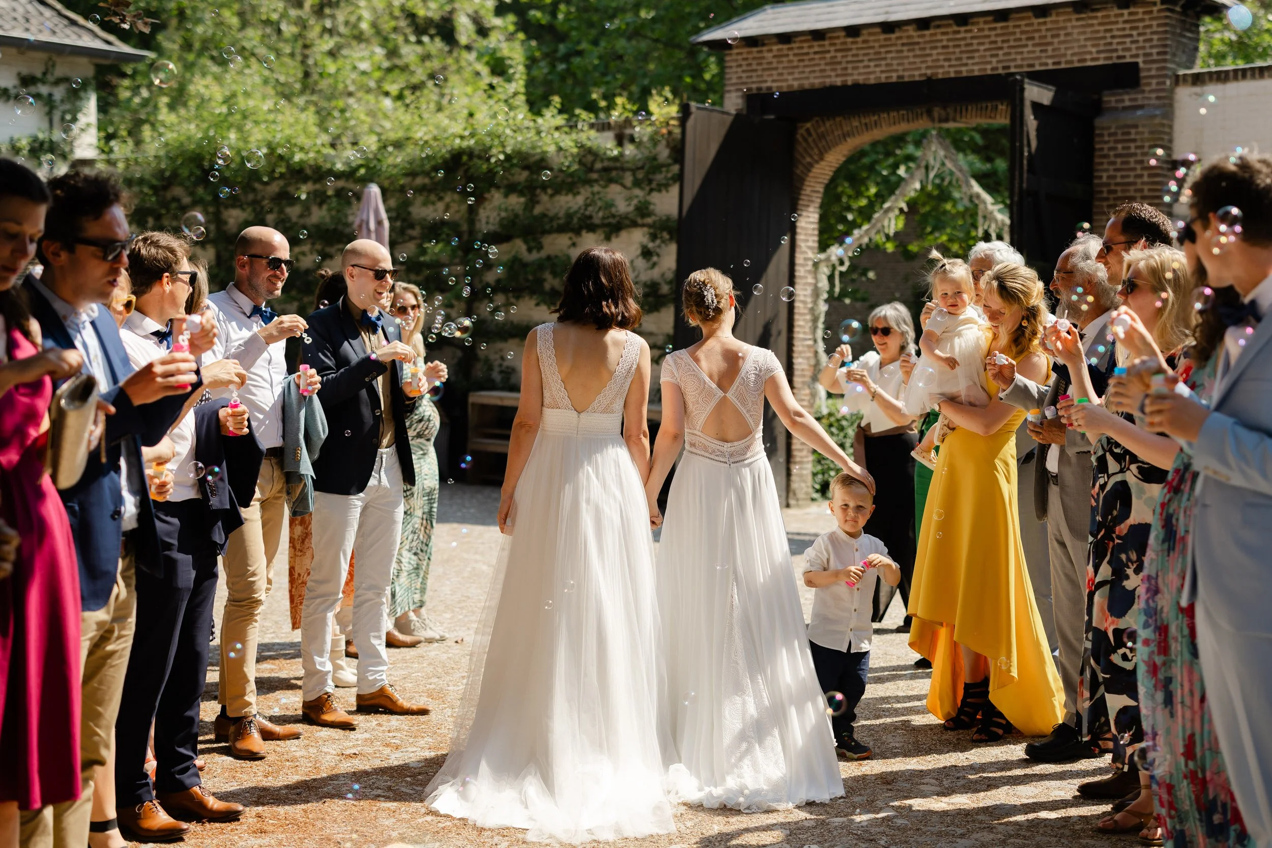 Bruidspaar loopt door een erehaag van gasten na de ceremonie, spontaan moment tijdens de borrel op een bruiloft