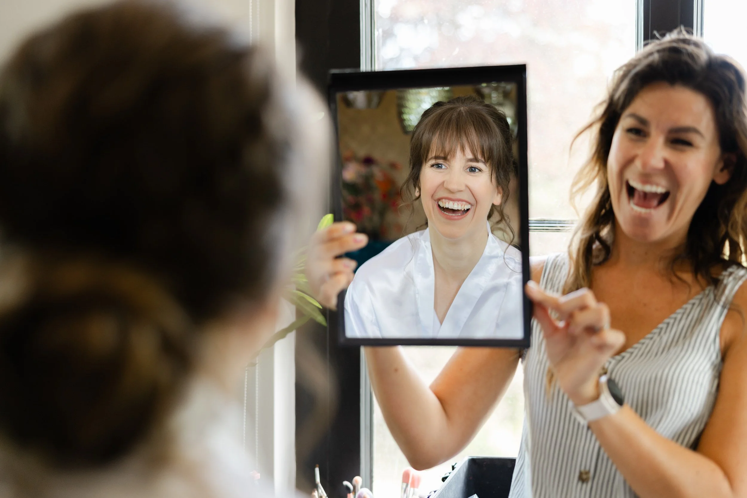 Vrolijk moment tijdens de voorbereidingen waarbij een vrouw via tablet meekijkt met de bruid op de trouwdag
