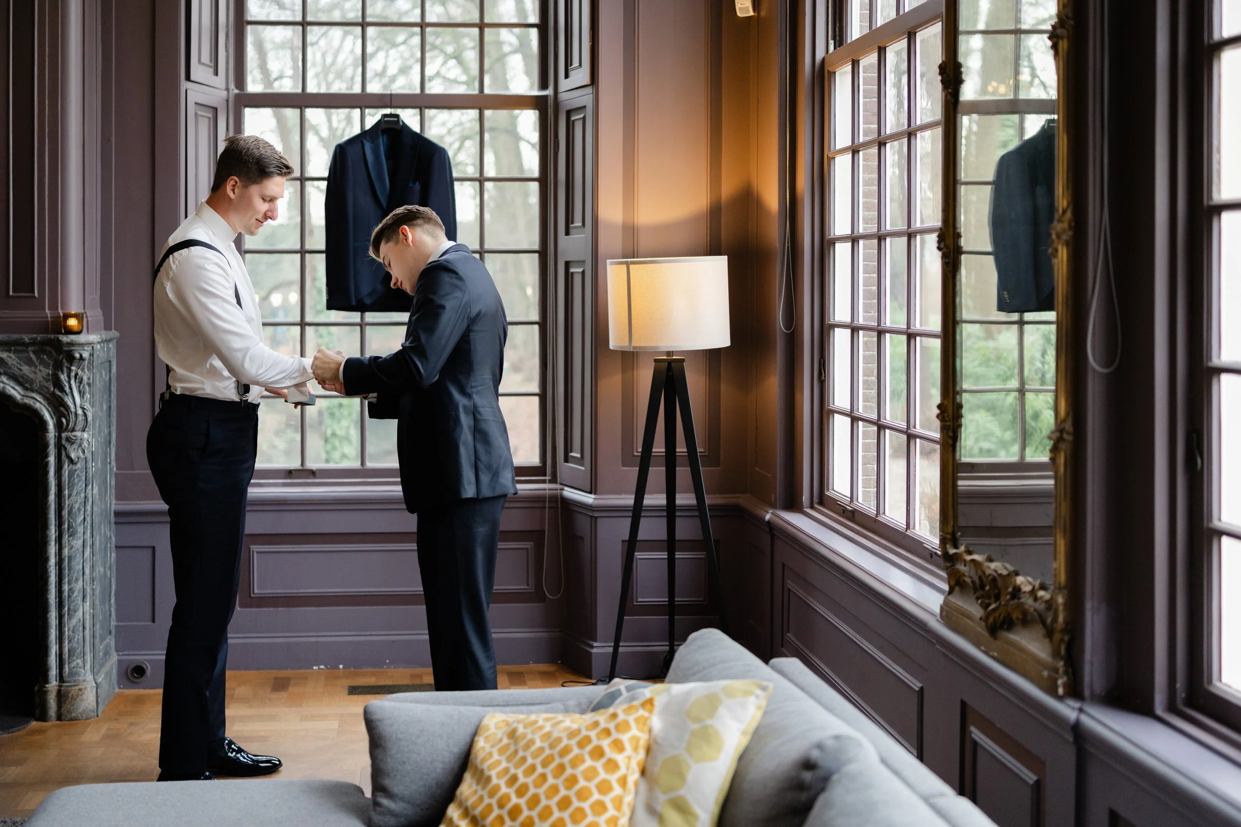 Bruidegom maakt zicht klaar bij het raam tijdens de voorbereidingen op de trouwdag, rustig en stijlvol reportagebeeld