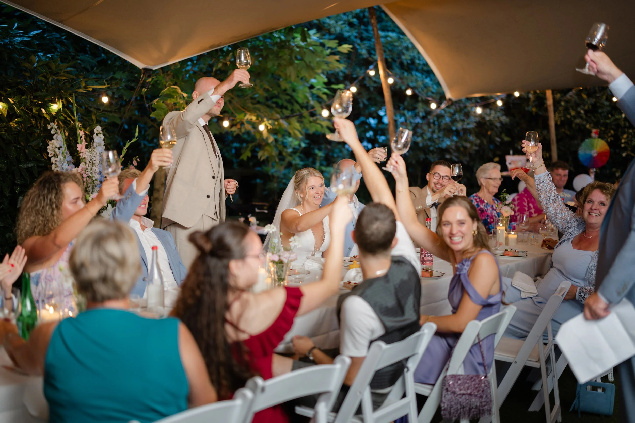 Gasten proosten en vieren samen tijdens het diner op een zomerse bruiloft in de buitenlucht