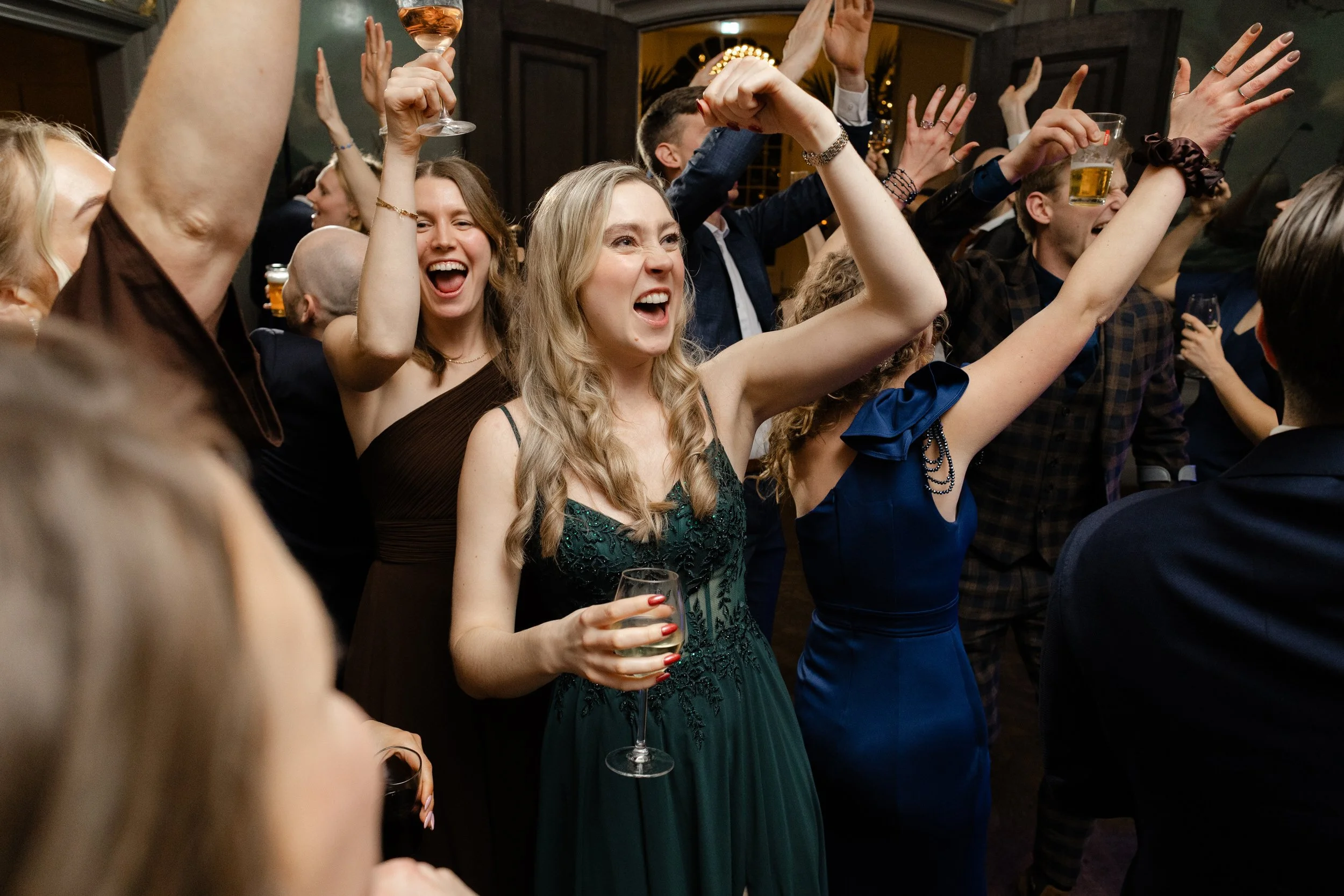 Gasten vieren feest en dansen met drankjes in de hand, vrolijk moment op een drukke dansvloer tijdens de bruiloft