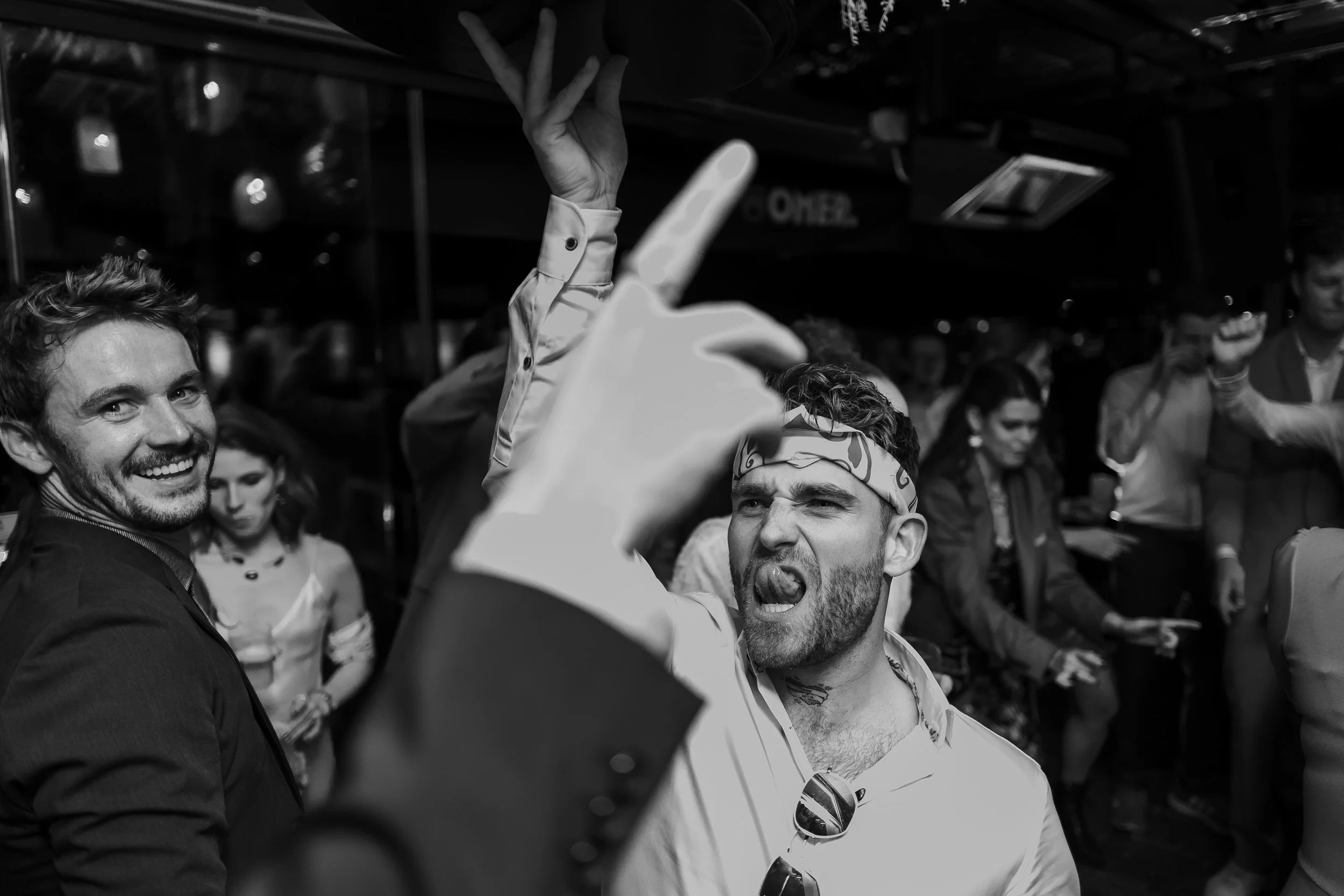 Zwart wit foto van gasten die losgaan op de dansvloer tijdens het avondfeest van de bruiloft