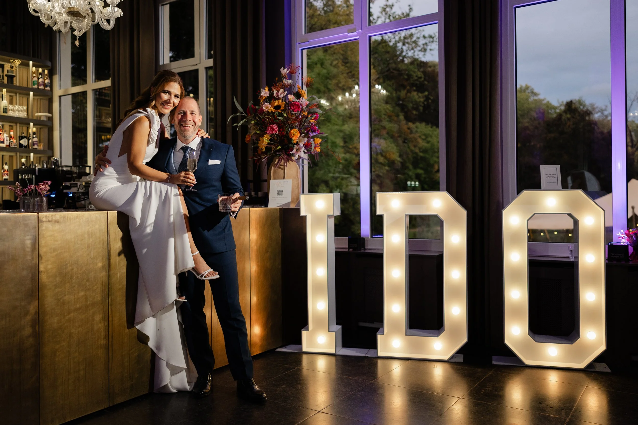Bruidspaar poseert samen bij grote verlichte letters tijdens het avondfeest op de bruiloft bij Delbrock Maastricht