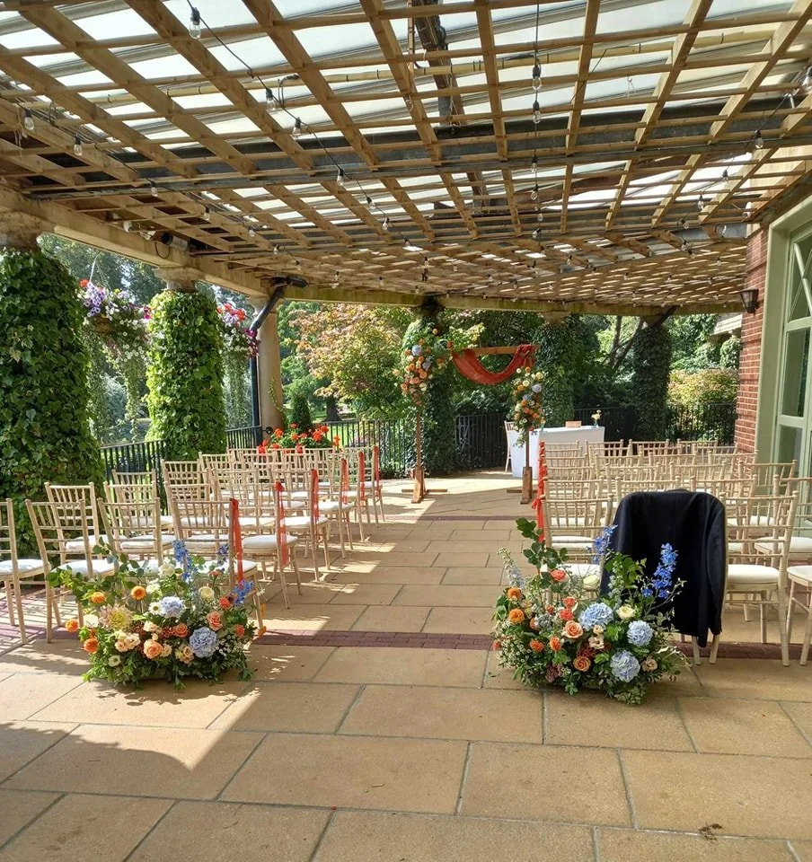 Outdoor wedding chairs on the terrace at the Sun Pavilion with blue and peach flower decorations