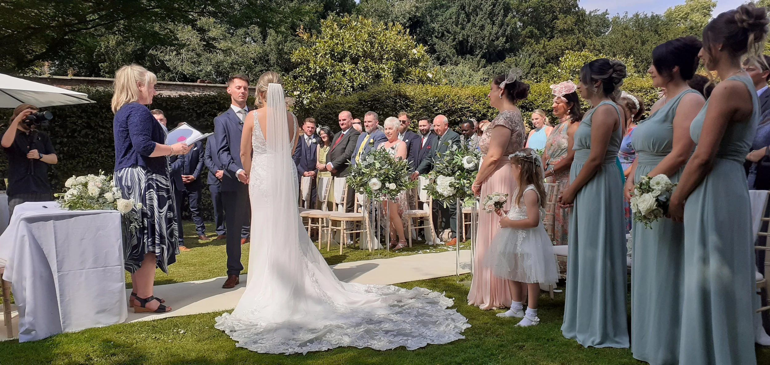 Bride and Groom stand at the top of the aisle in the garden of Saltmarshe Hall