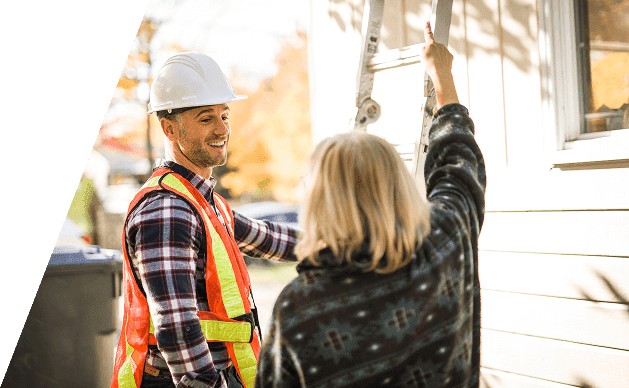Contractor in a safety vest consulting with a homeowner near a ladder.