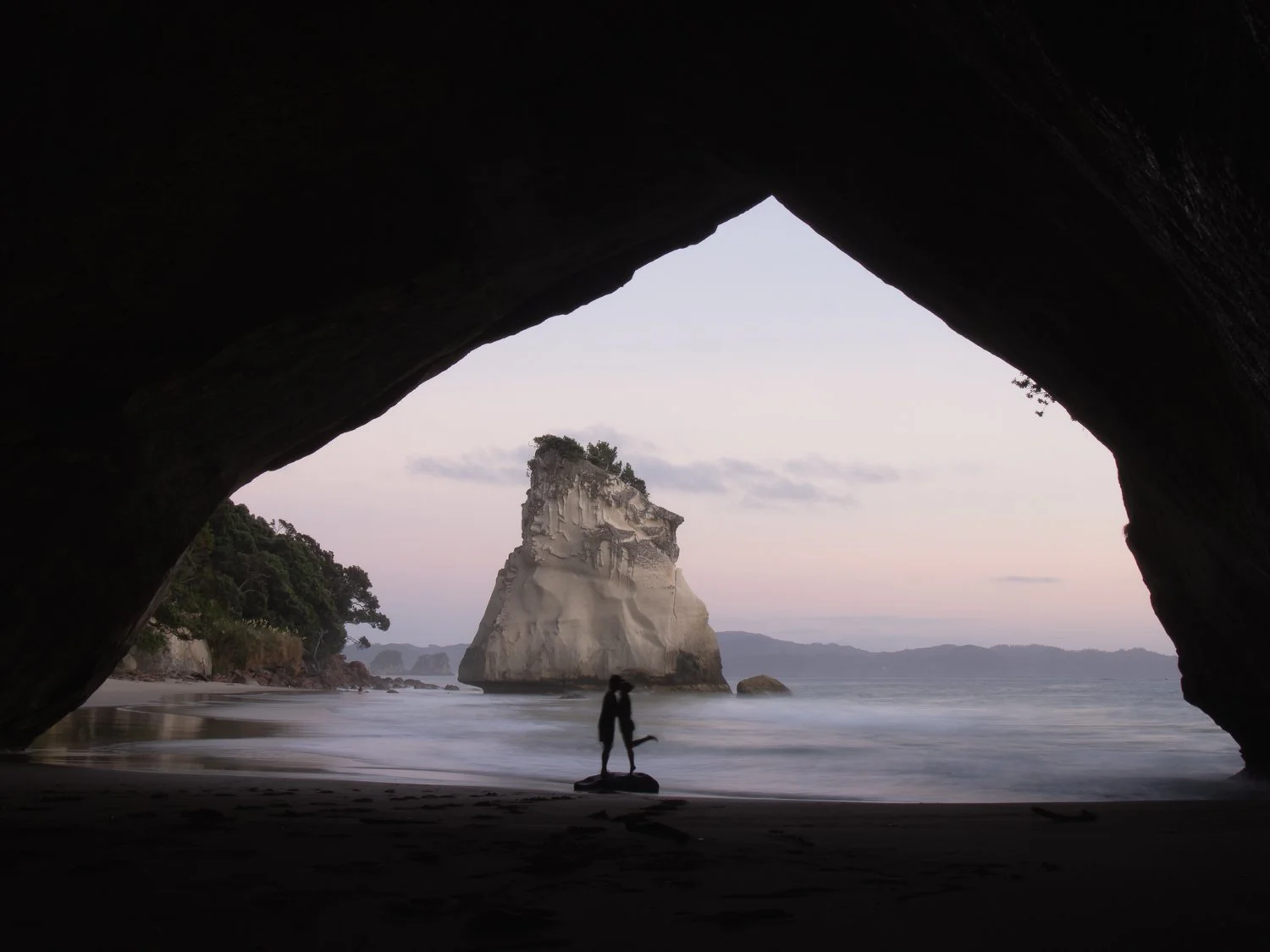 A couple kissing on sandy beach during sunrise.