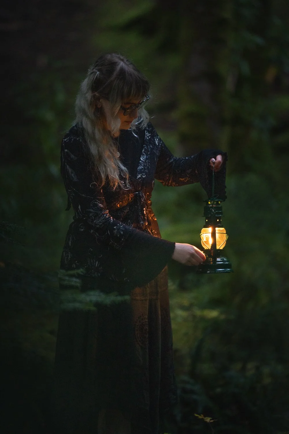 Model in black dress holding lantern.