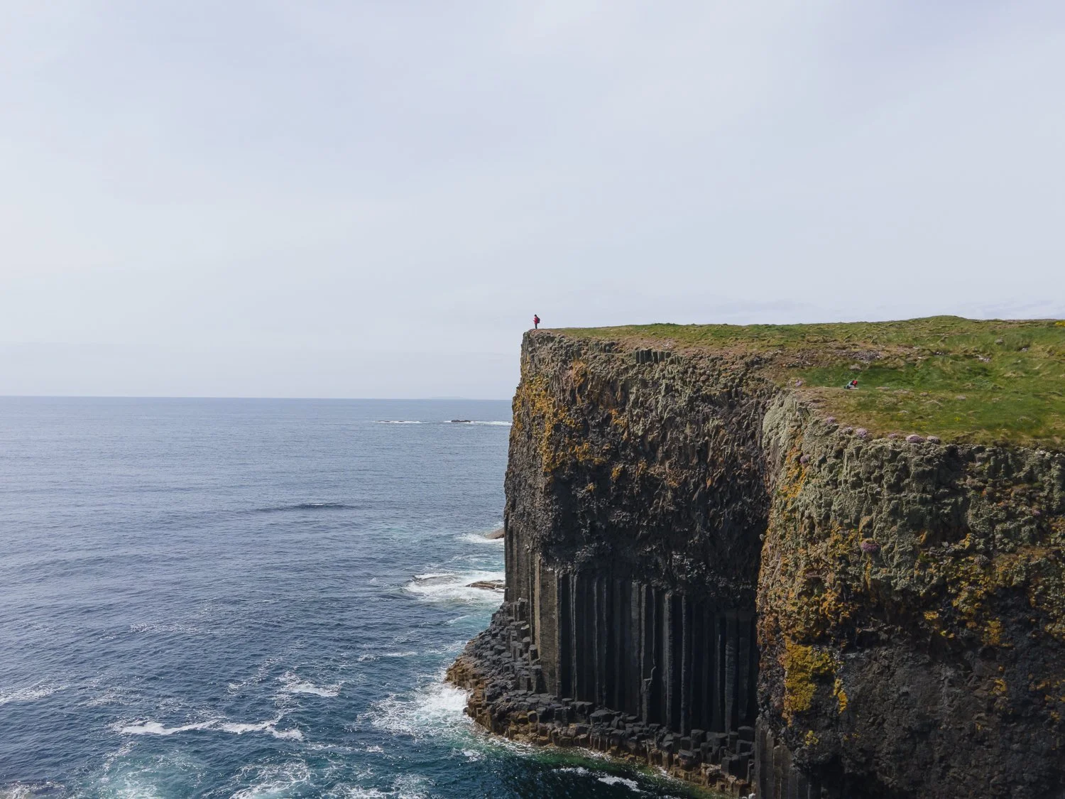 A person standing on the edge of a volcanic cliff.