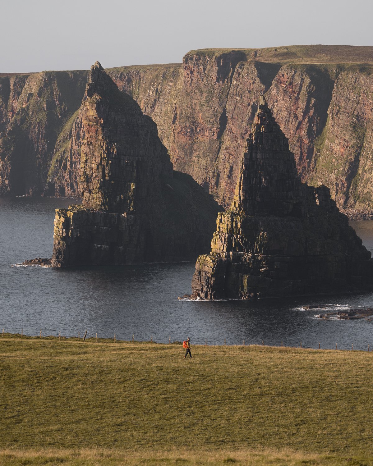Person walking in front of Duncansby Stacks. 