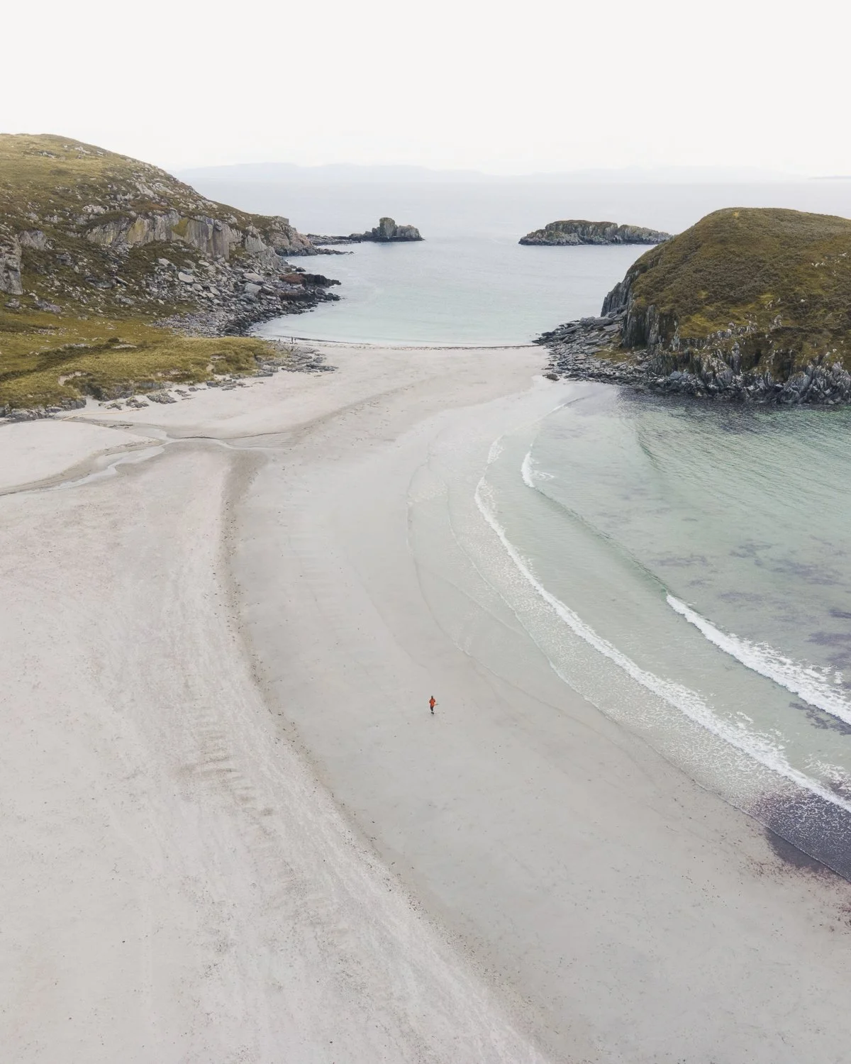 a lone person walking on the white sandy beach on the Isle of Mull.