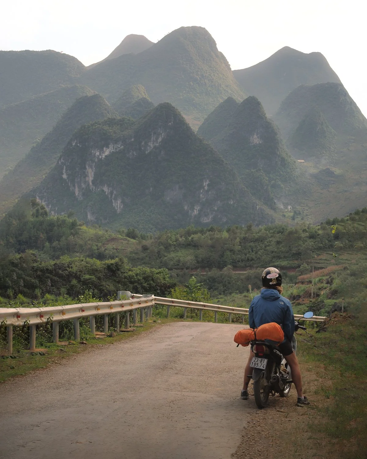 Jagged peaks of Northern Vietnam with a person on a motorbike in the foreground.