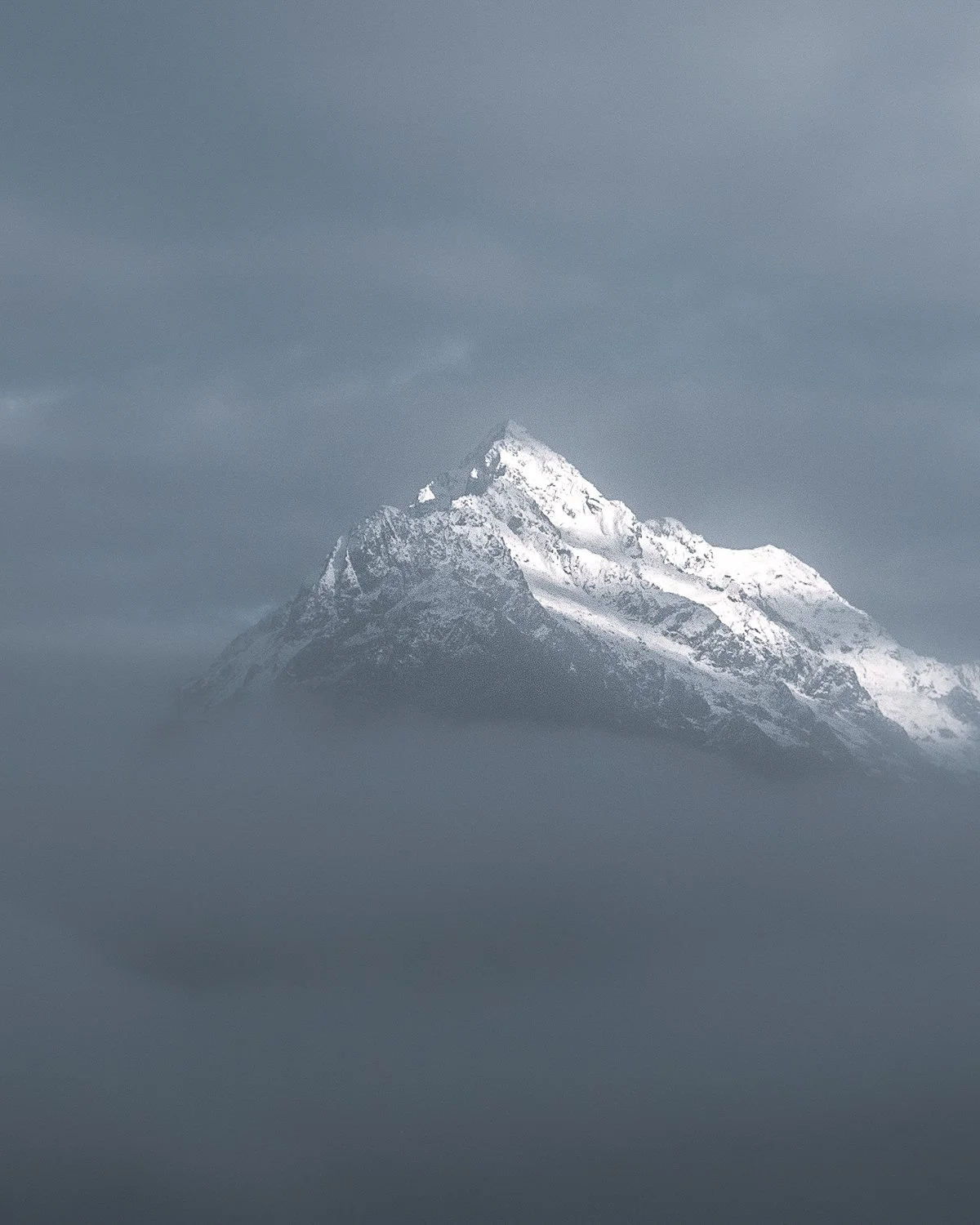 Snow-capped mountain peak shrouded in clouds.