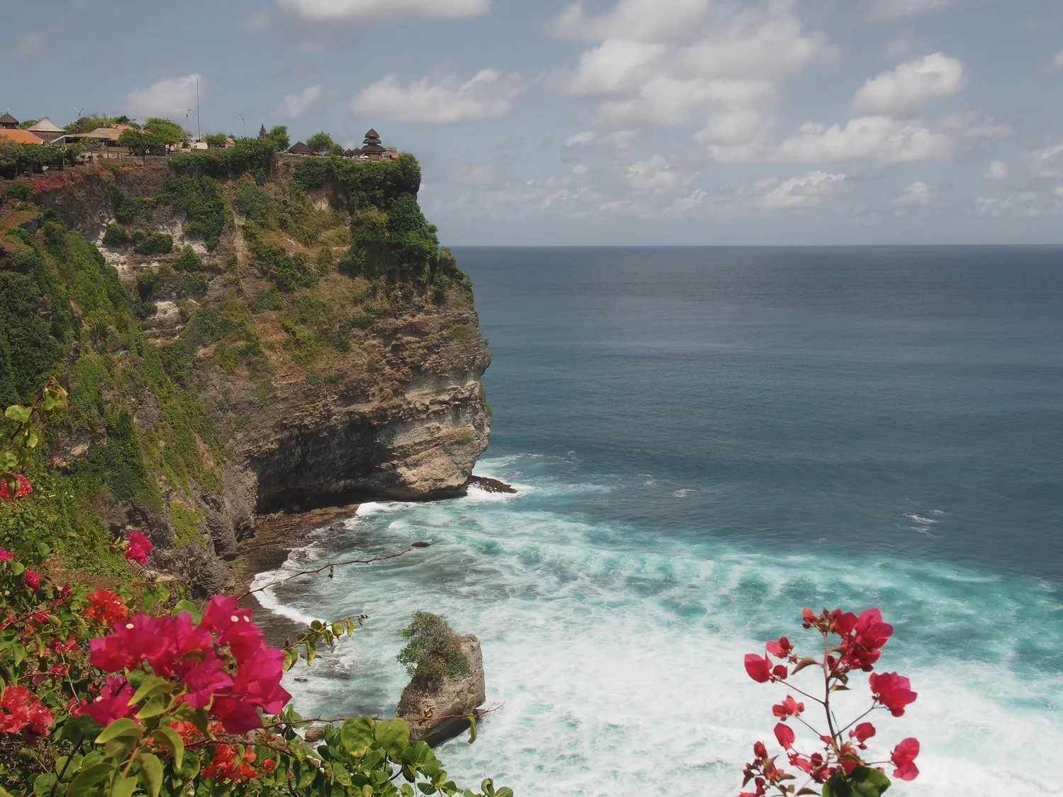 Panoramic view of a temple perched on the edge of a cliff.