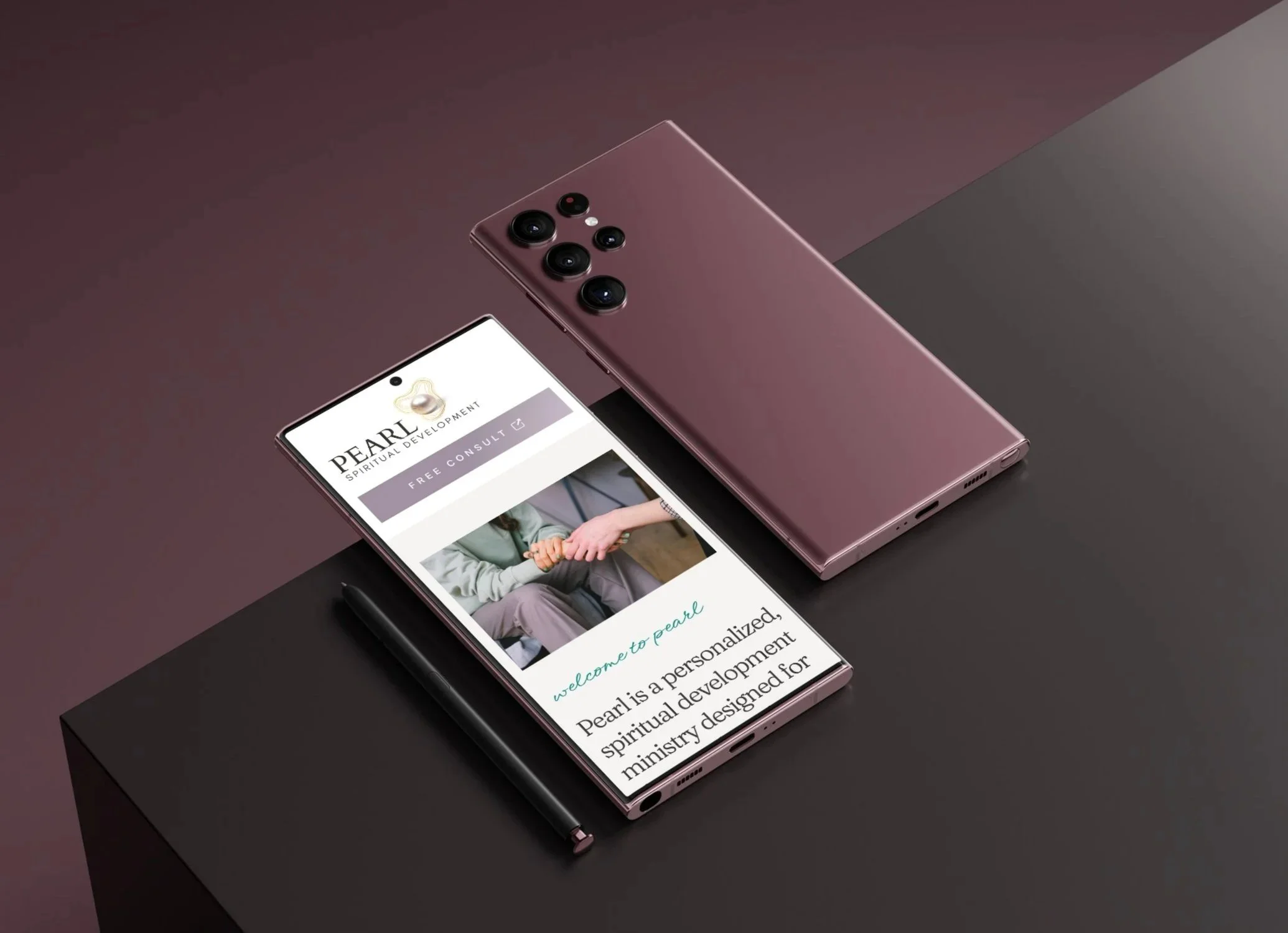 A smartphone displaying the PEARL spiritual development website, placed on a dark surface with a black pen beside it, and a second pink phone with multiple camera lenses in the background.