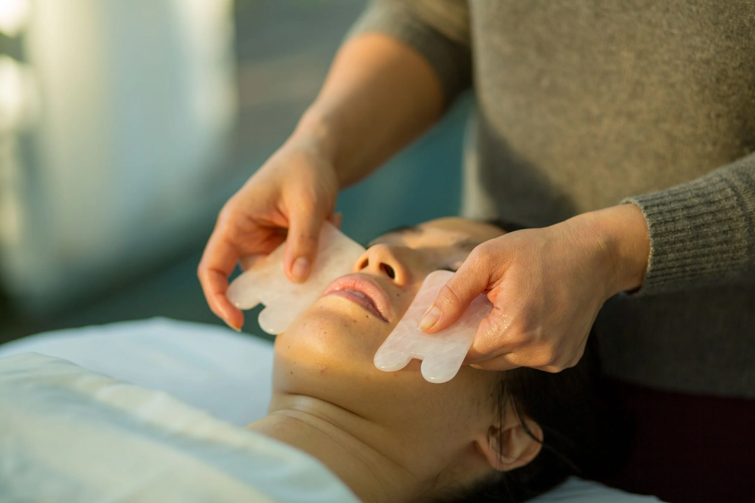 Woman receiving a gua sha treatment to her face.