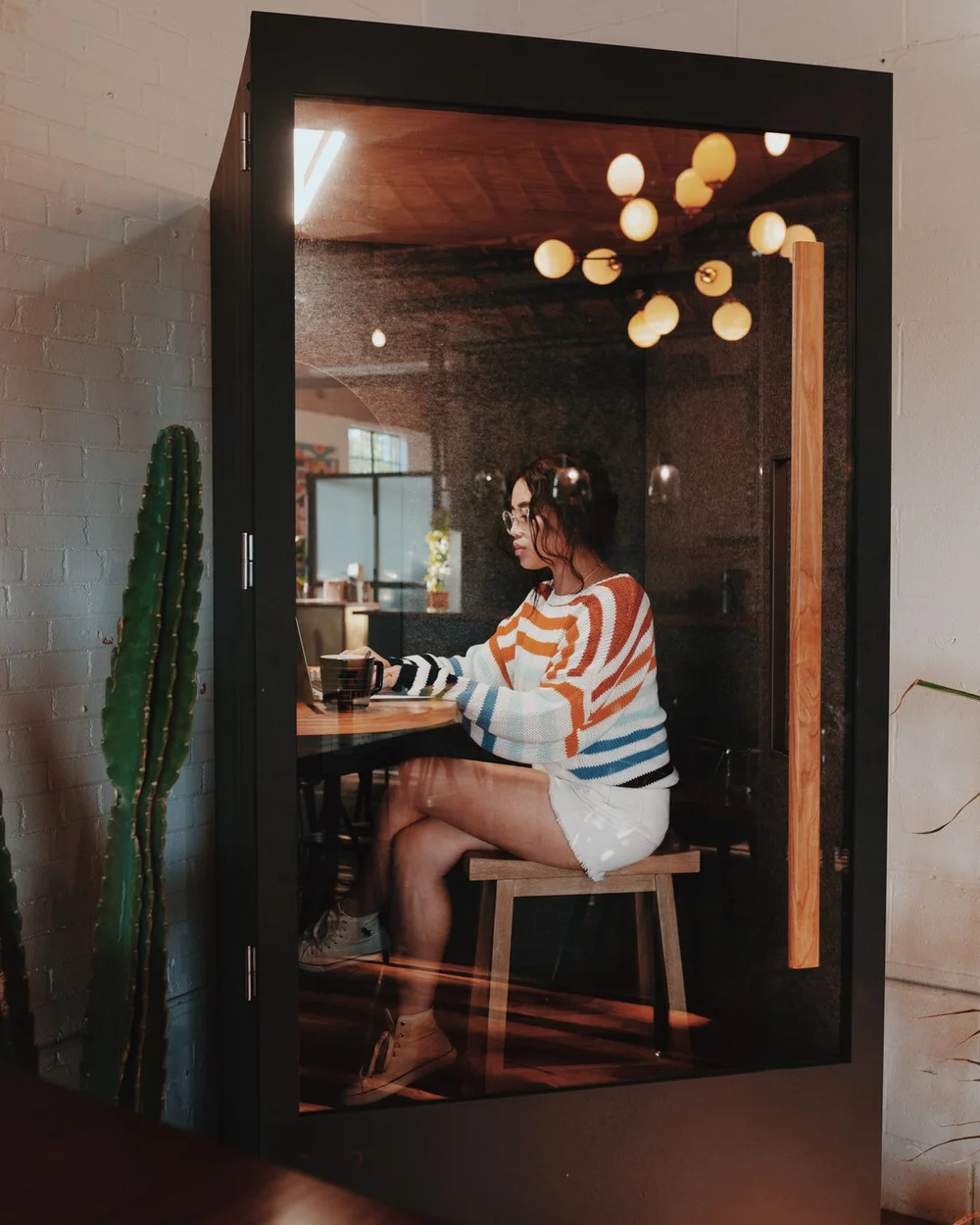 A member working inside a glass phone booth at Wax Space