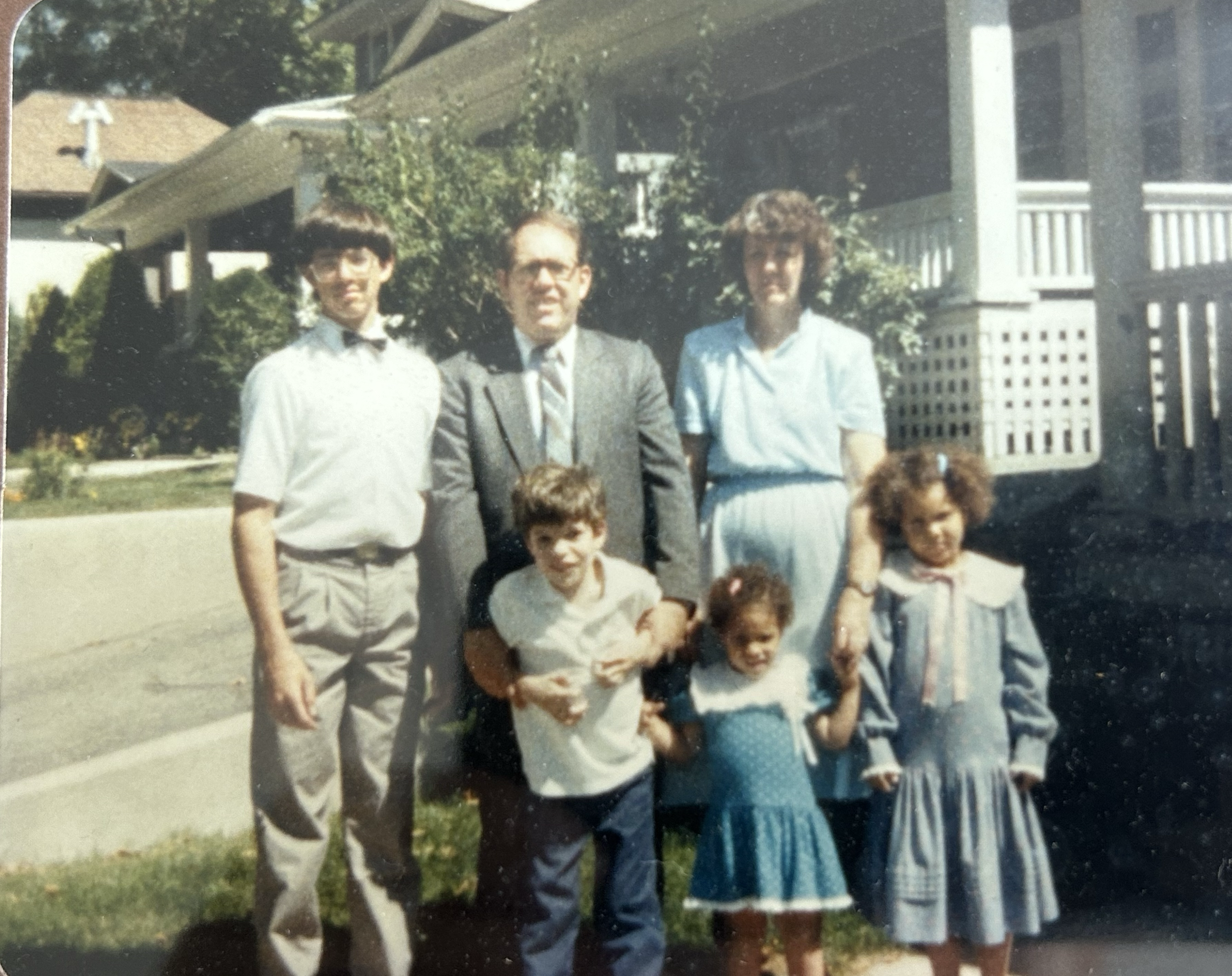 These images are shared by Melanie to offer a warm glimpse into her story and lived experience within adoption.

Description of Image:
This is a photo of Melanie with her family—her parents, her older brothers, and her younger sister. One of her brot