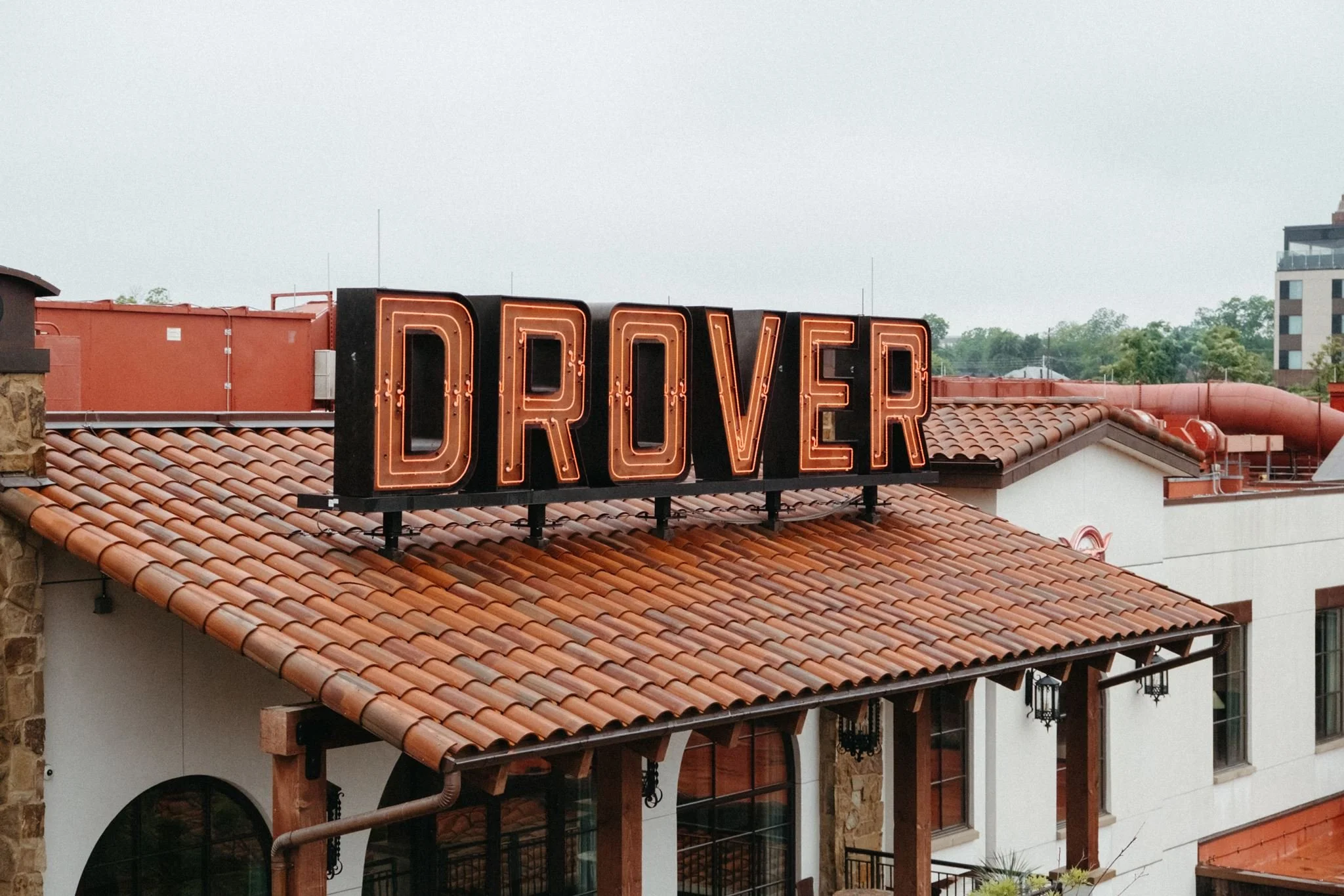 A neon Hotel Drover sign mounted on a red tile roof.