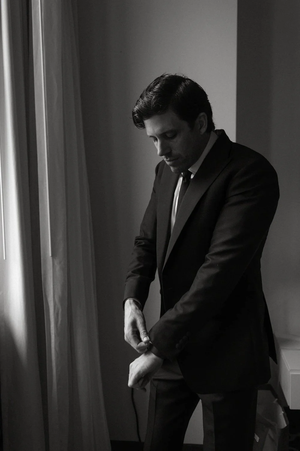A man in a suit adjusts his sleeve cuff, captured by a Dallas wedding photographer.