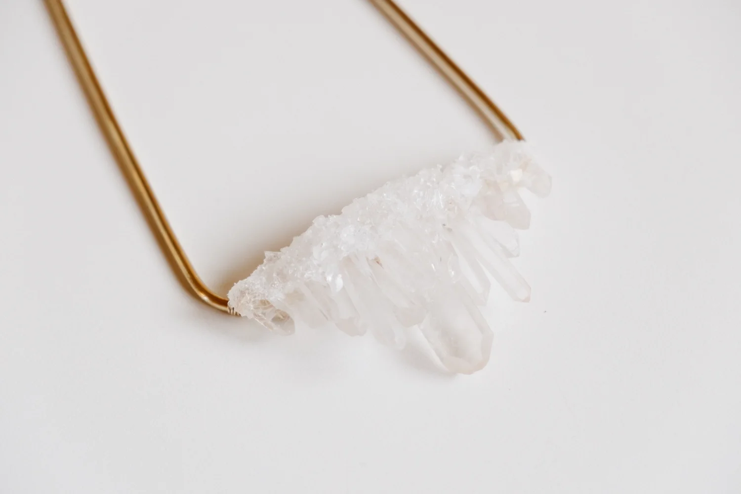 Close-up of a necklace with a row of white, crystalline, elongated beads on a white background.