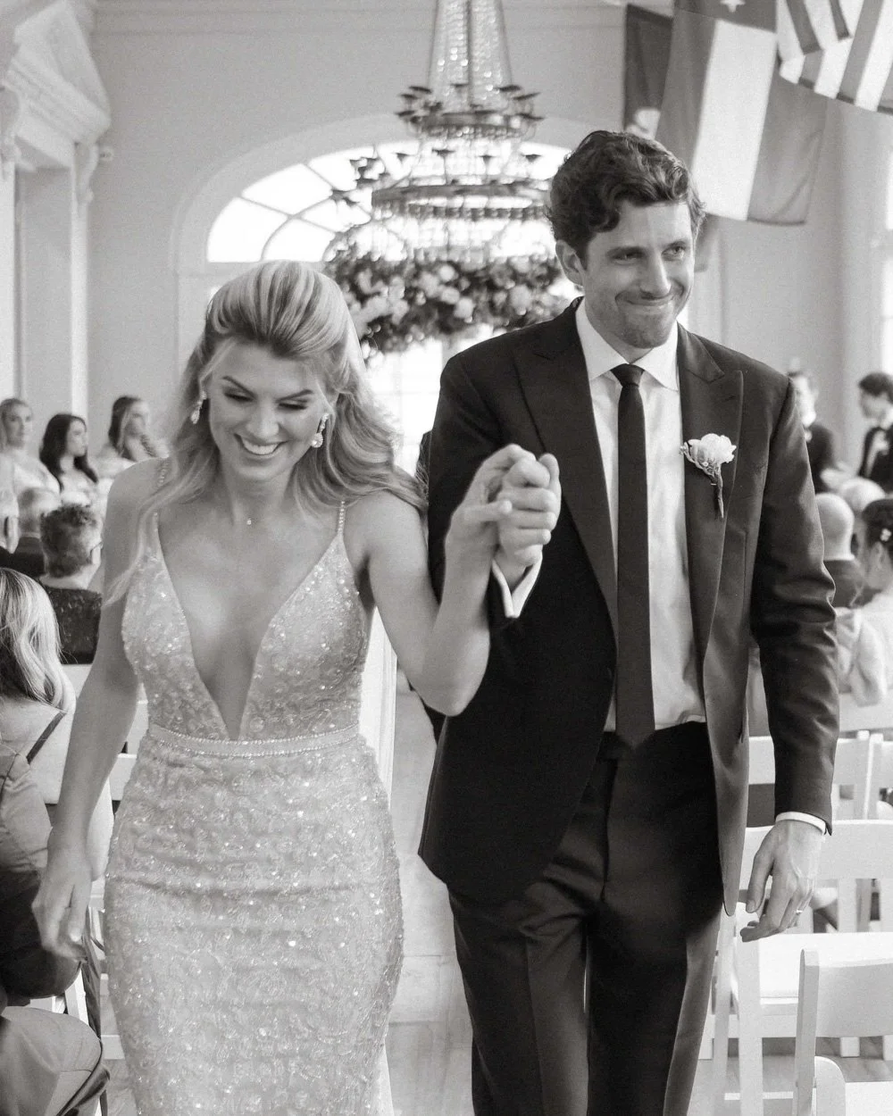 A smiling bride and groom walk hand in hand down the aisle, as captured by a Dallas wedding photographer.